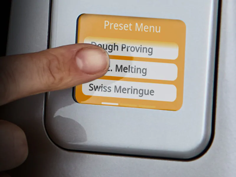 Nahaufnahme eines Fingers, der ein Menü auf einem weißen Gerät berührt.