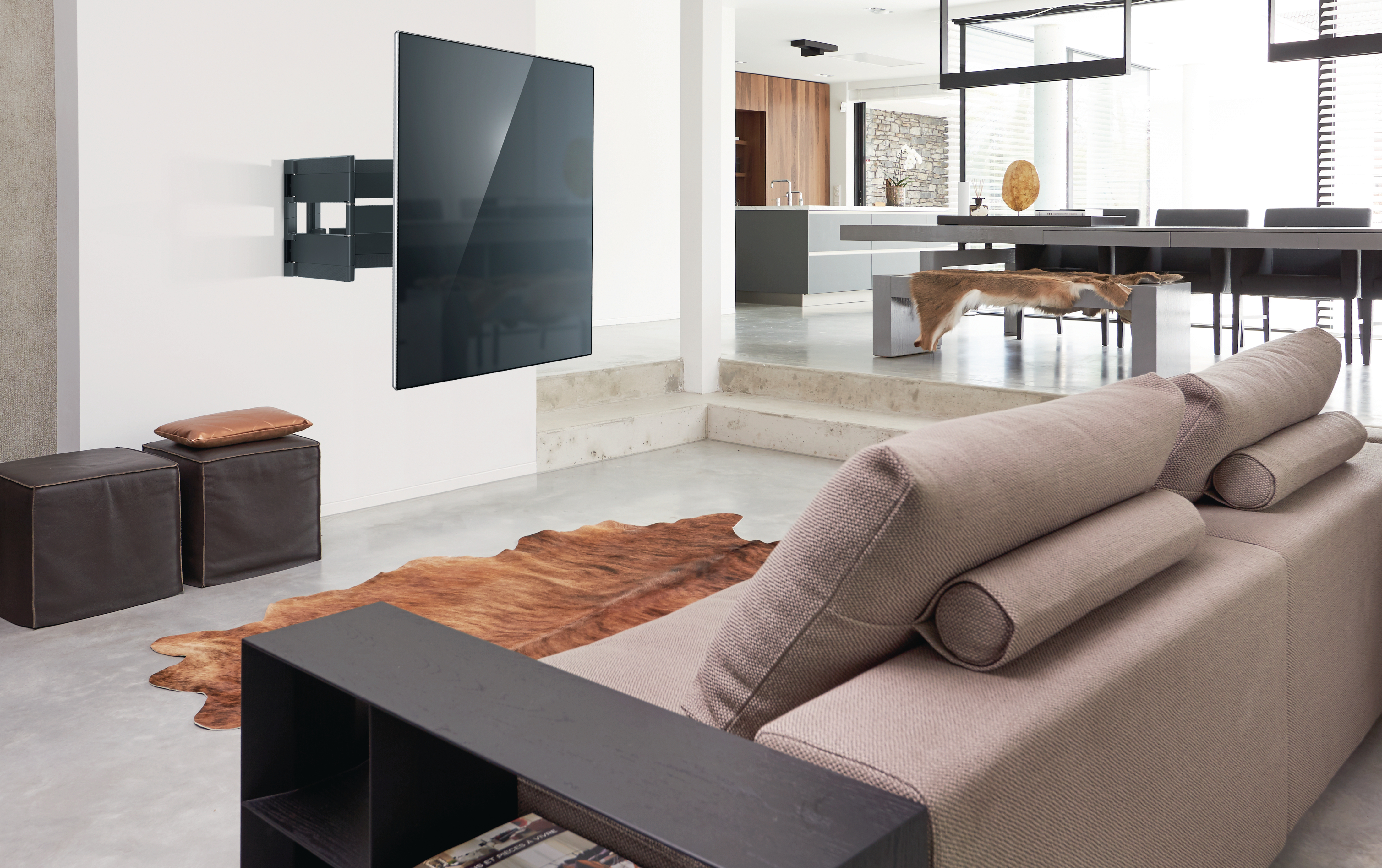 Wohnzimmer mit an der Wand montiertem Fernseher und braunem Sofa. Der Raum hat ein modernes Design.