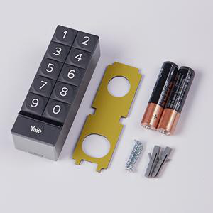 Yale-Tastatur, goldene Platte, Schrauben, Batterien und Wandanker auf weißer Oberfläche. Zahlen 0-9 auf der Tastatur.