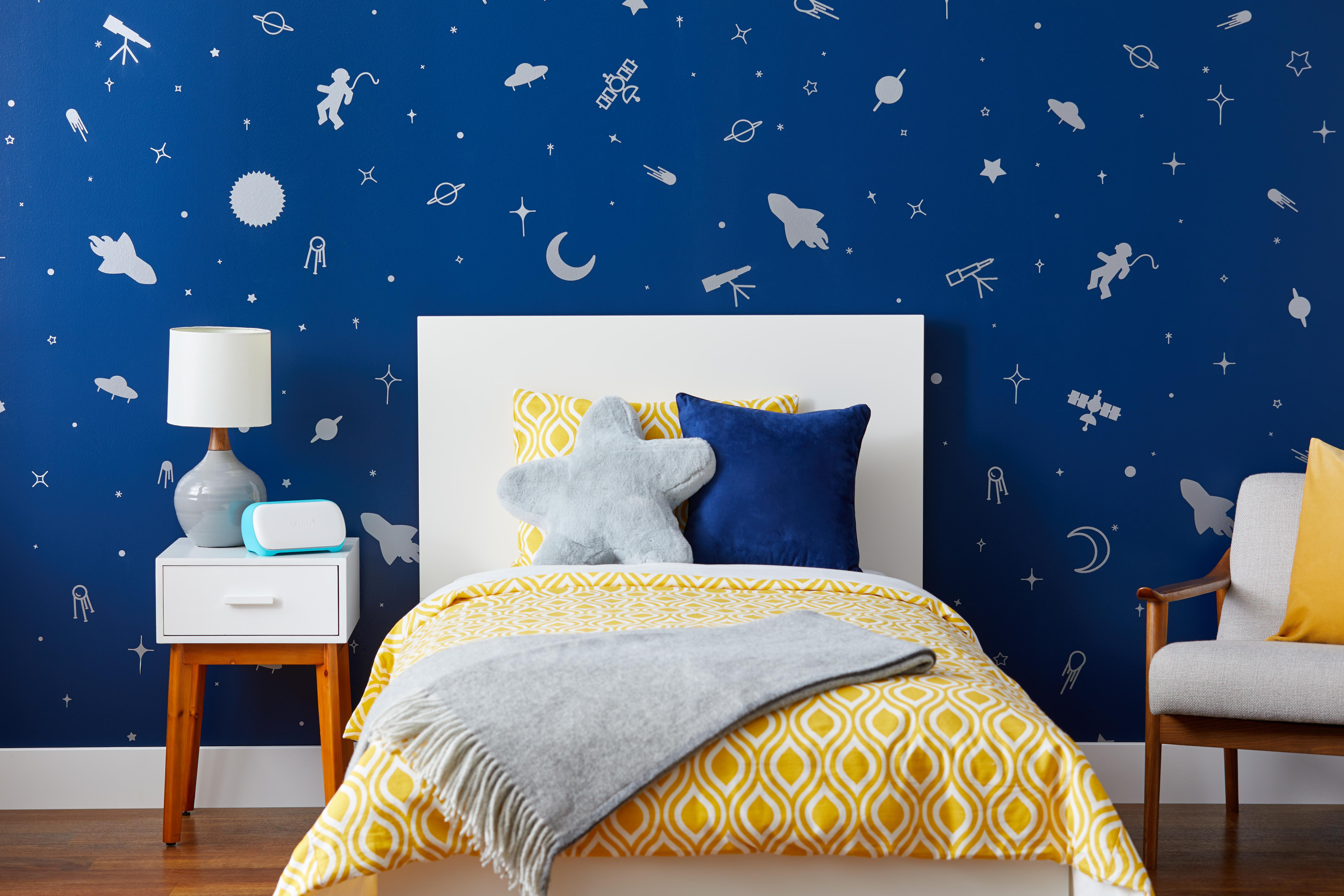 Kinderzimmer mit Weltraummural, Bett mit gelbem Musterbettzeug und Nachttisch.
