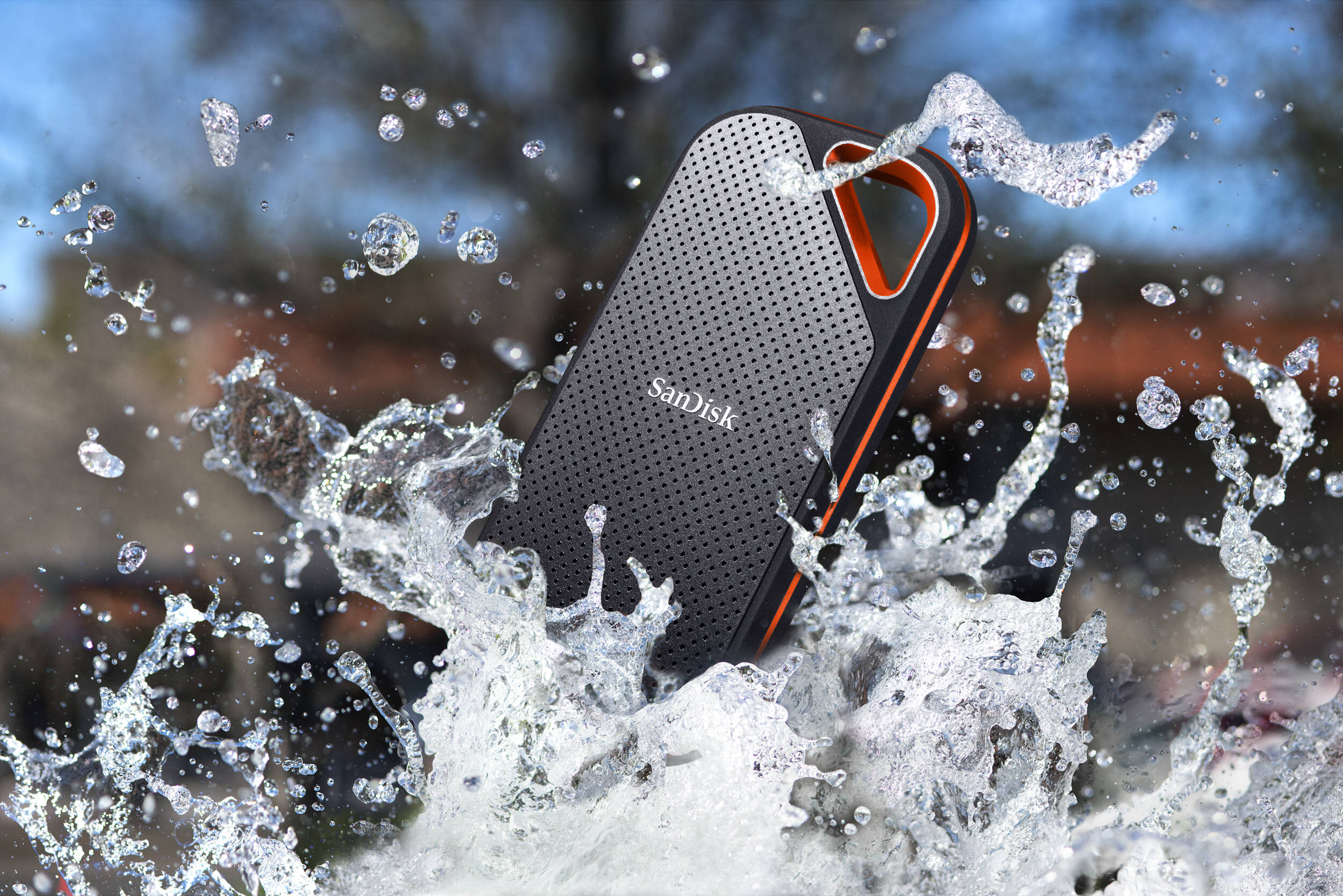 Hard disk esterno Sandisk nero e arancione con spruzzi d'acqua.