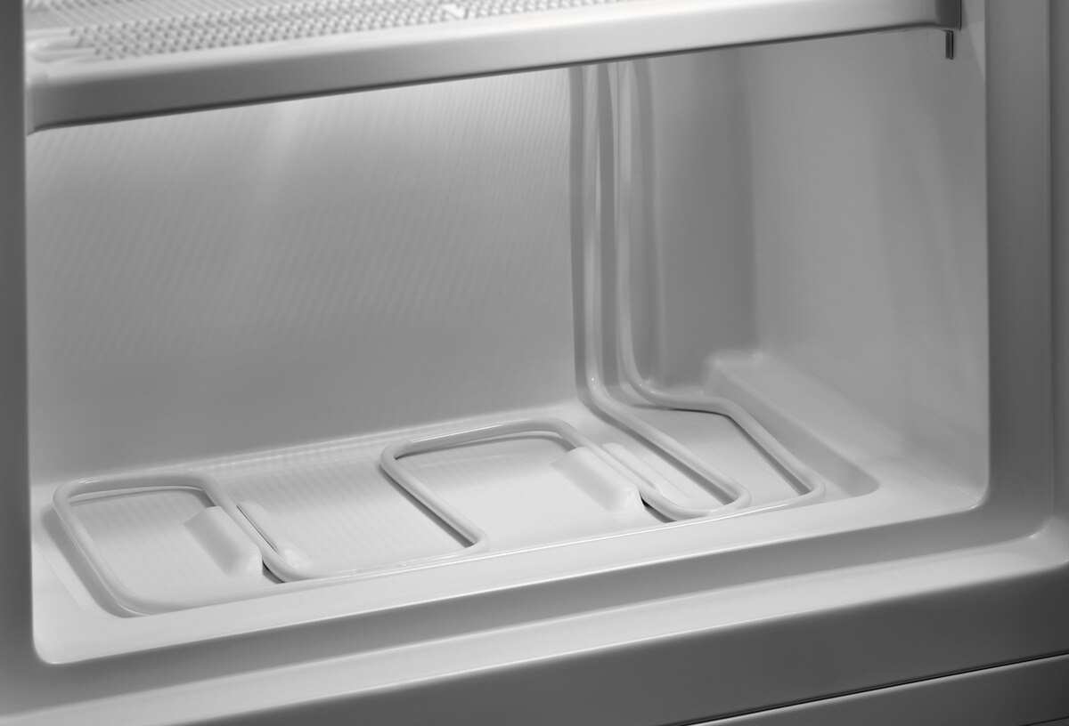 Interior of a refrigerator with shelves and a cold air outlet.