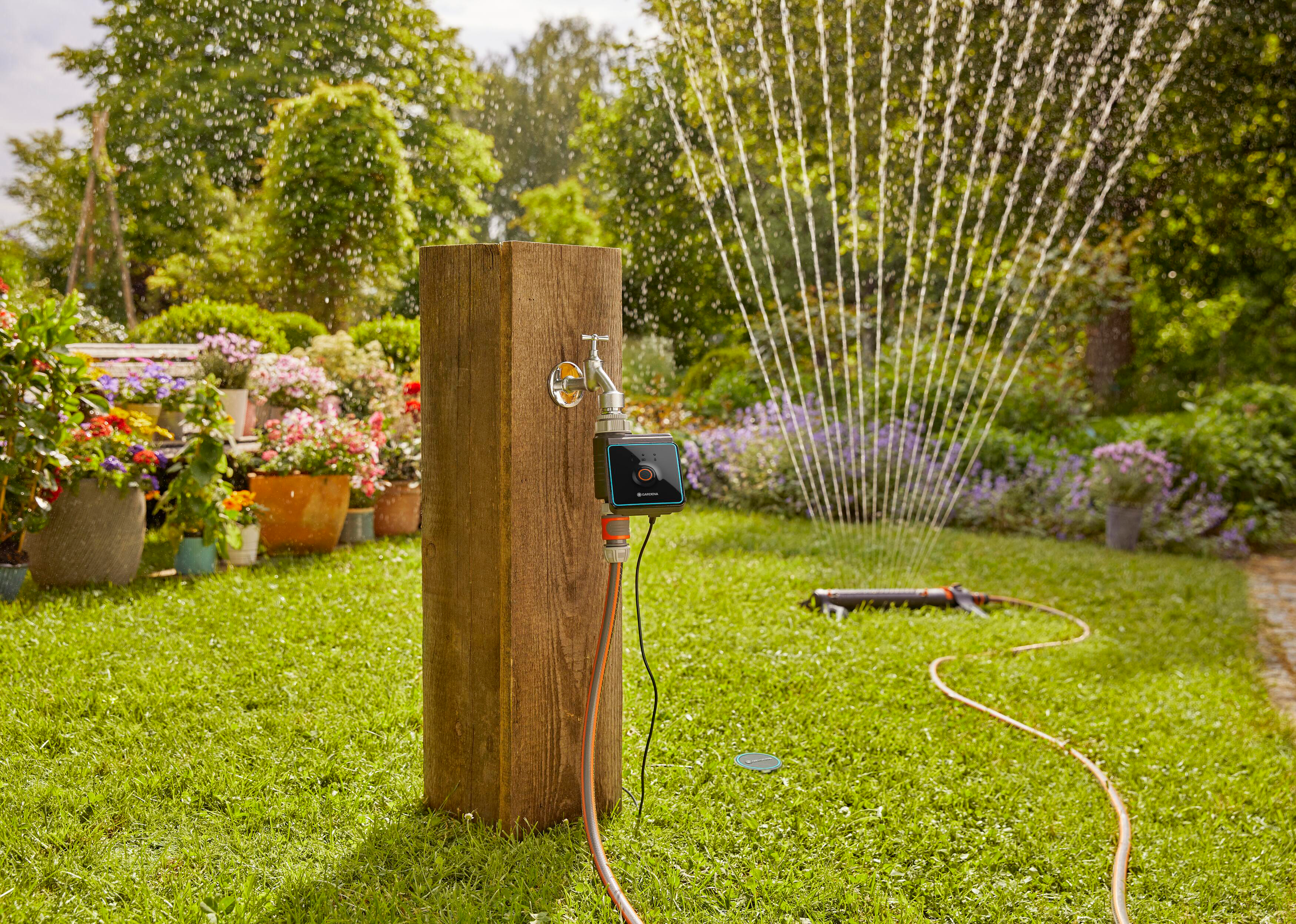 Eine Gartenszene mit Rasensprenger, Holzpfosten und Bedienfeld.