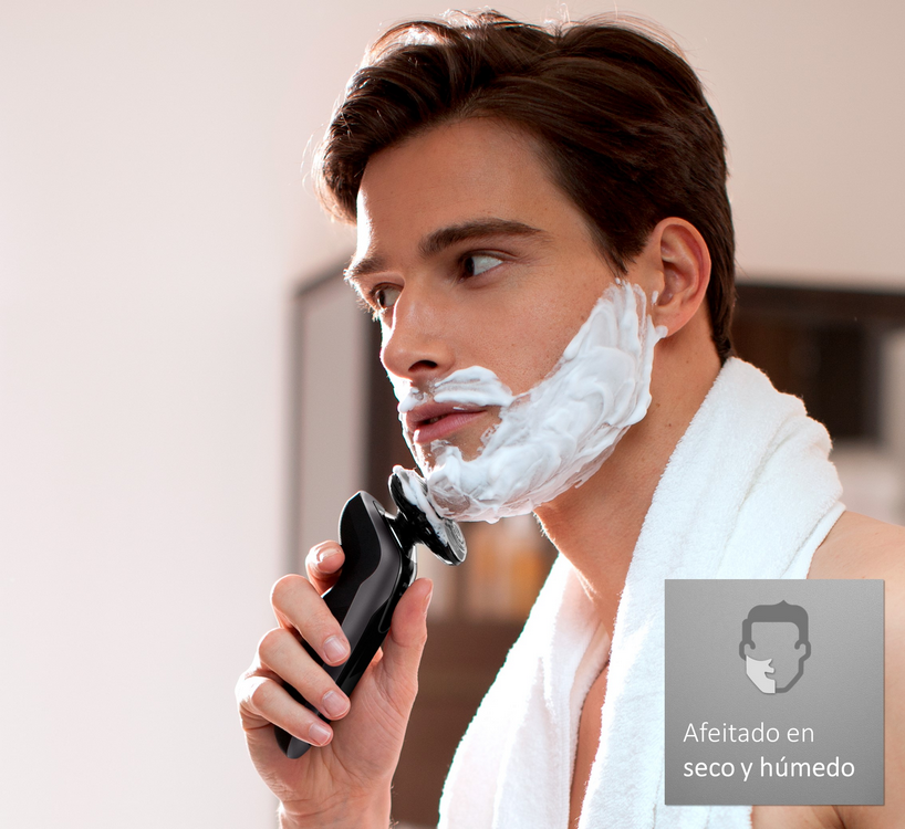 Hombre afeitándose con maquinilla eléctrica, con crema de afeitar en la cara.