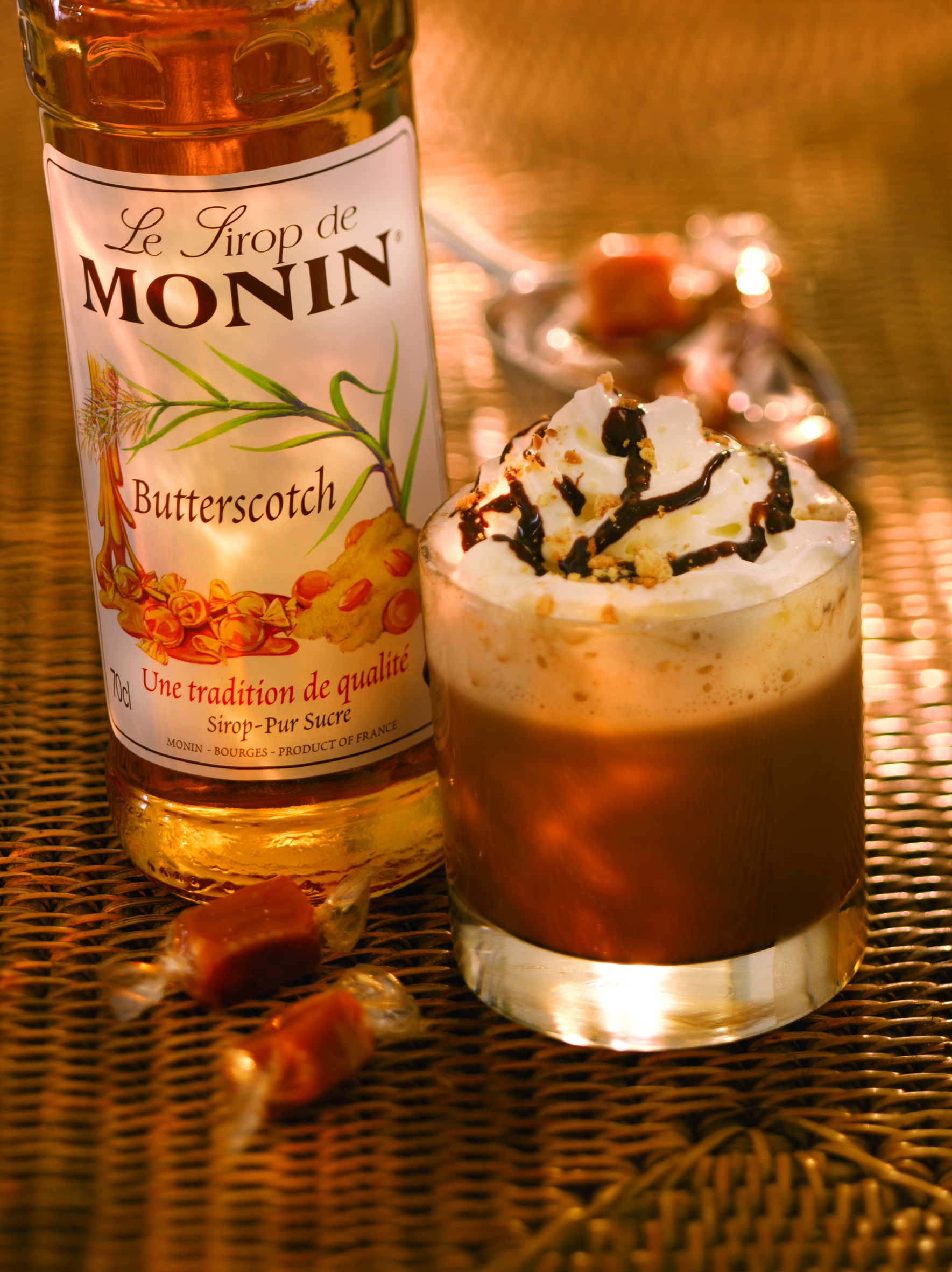 Eine Monin Butterscotch Sirup Flasche und ein Glas Kaffee mit Butterscotch-Geschmack.