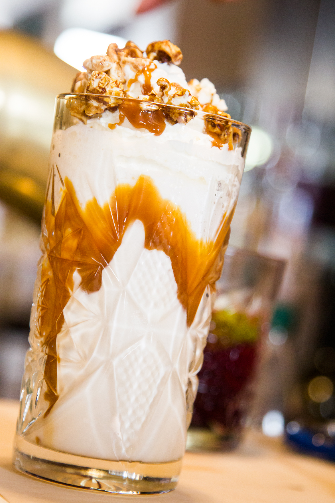 Hohes Glas mit geschichteten Zutaten. Karamellsauce tropft herunter, bedeckt mit Popcorn.