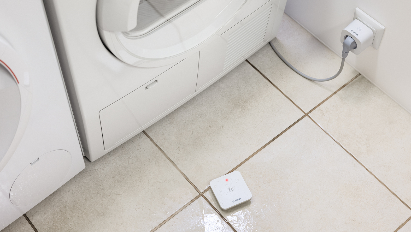 Weiße Geräte: Waschmaschine und Trockner, mit Smart-Stecker an der Wand.