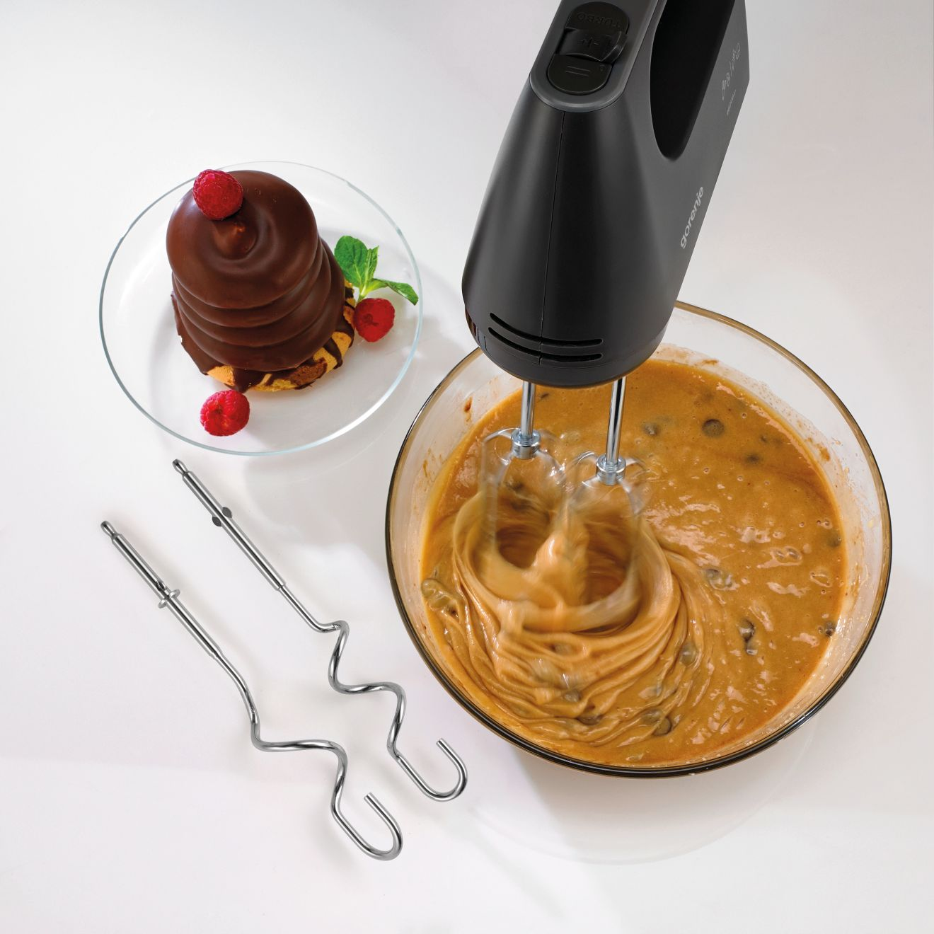 Egy kézi mixer tésztát ver egy üvegtálban.