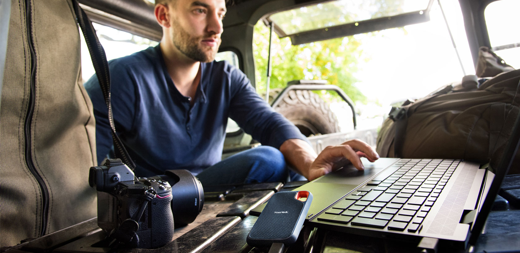 Ein Mann arbeitet an einem Laptop im Kofferraum eines Autos.