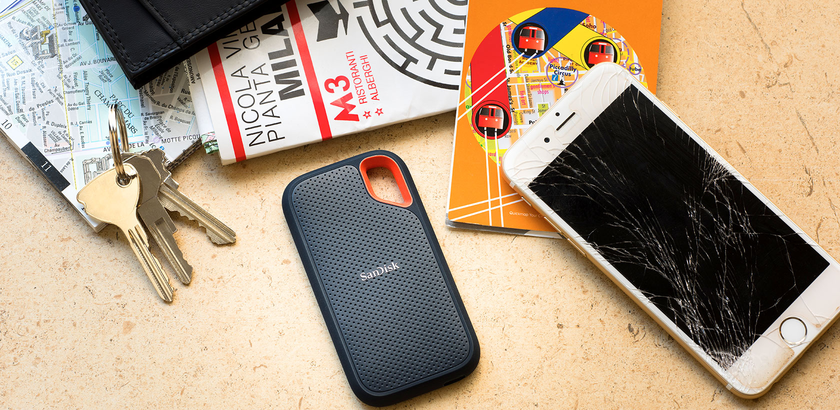 Eine Geldbörse, Schlüssel, ein kaputtes Telefon und SanDisk-Laufwerk auf einem Tisch.