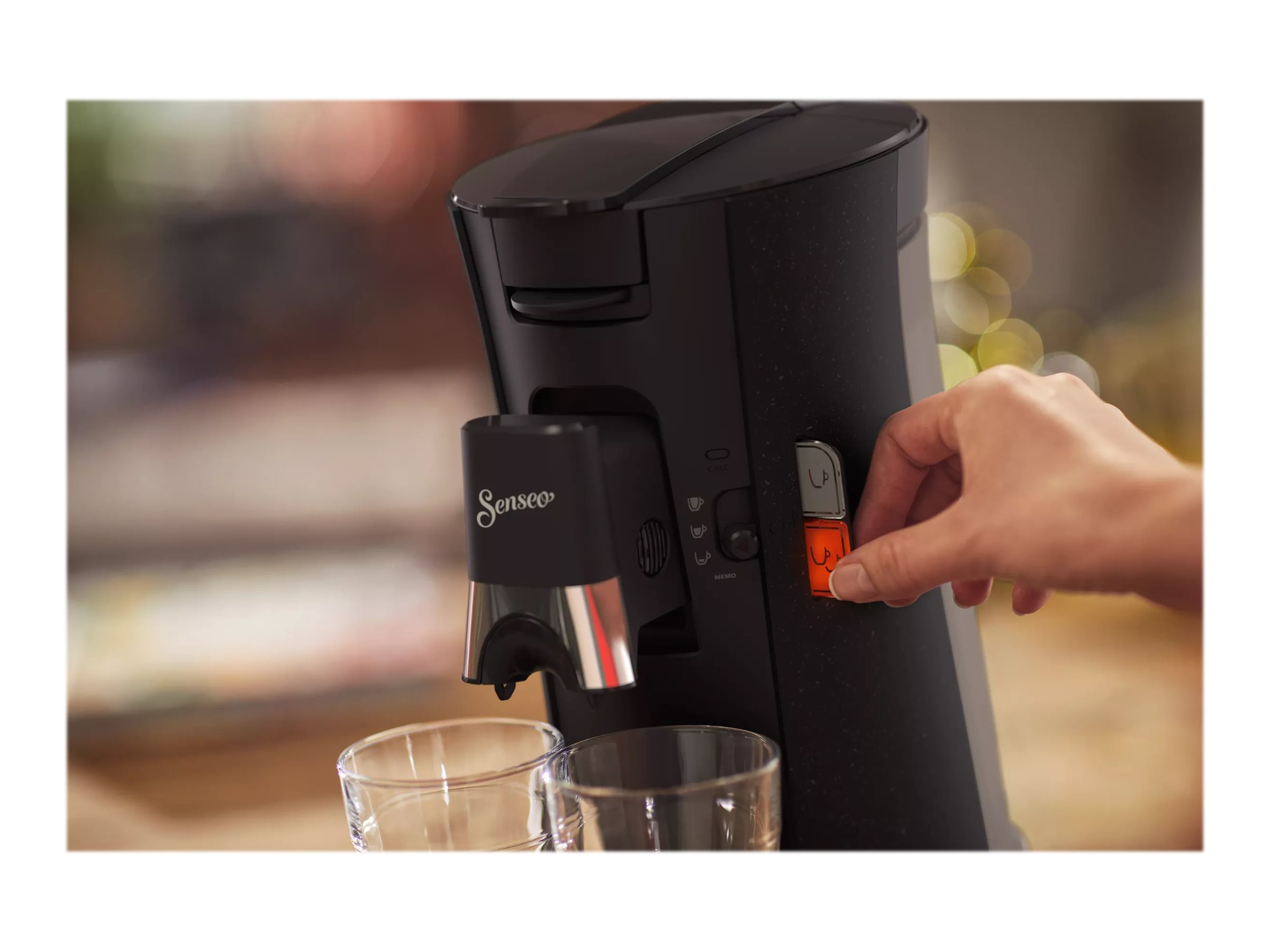 Nahaufnahme der Kaffeemaschine. Hand drückt einen Knopf. Schwarze und orange Farben.