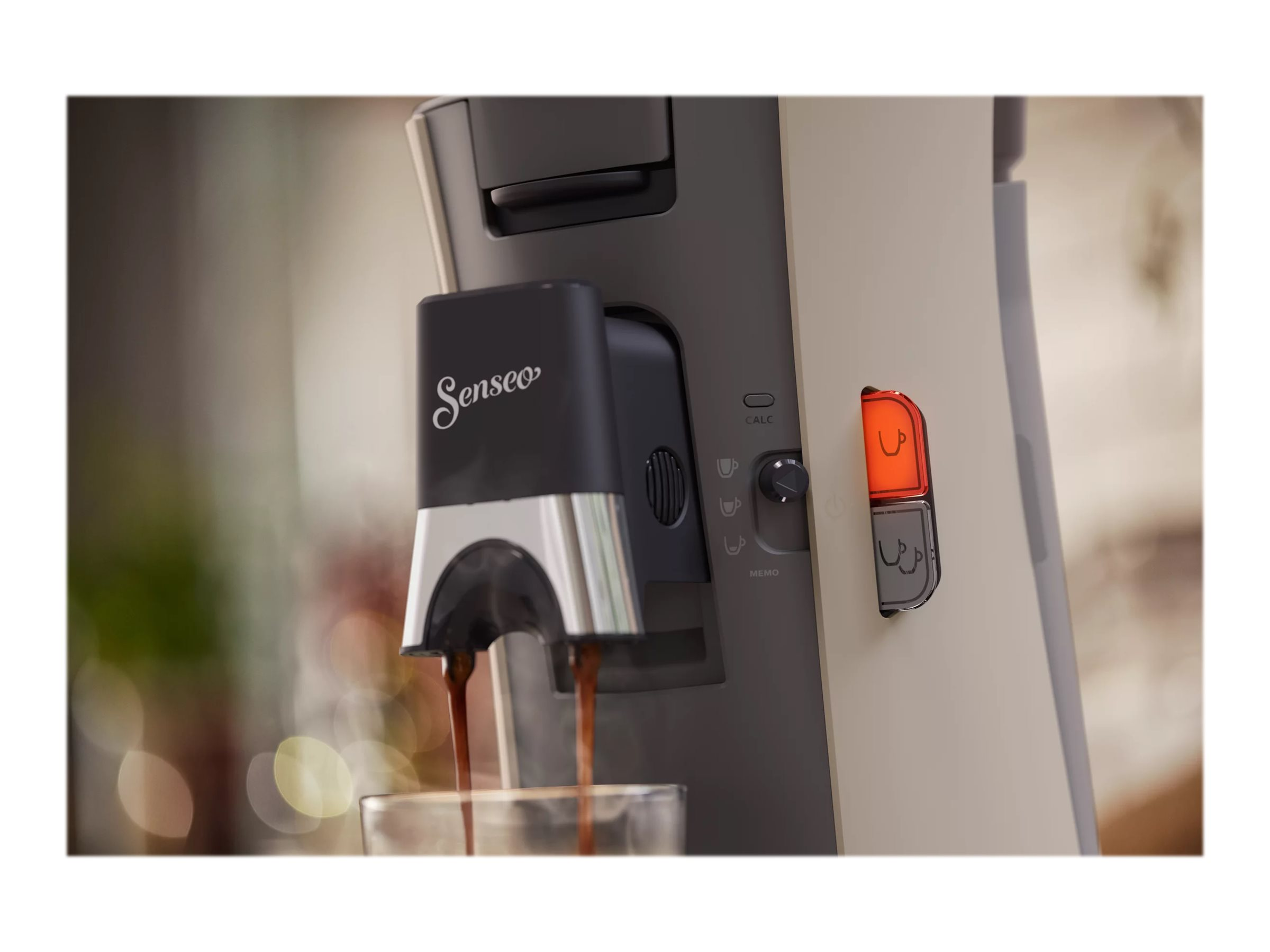 Eine Senseo-Kaffeemaschine, die Kaffee in ein Glas ausgibt. Die Maschine ist beige und schwarz.