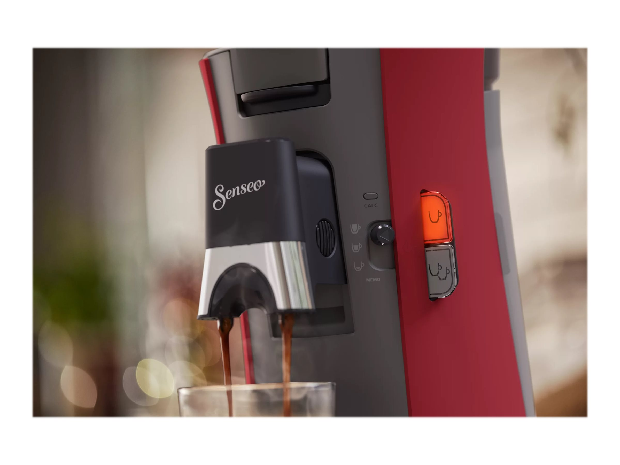 Nahaufnahme eines roten und grauen Kaffeeautomaten, der Kaffee einschenkt.
