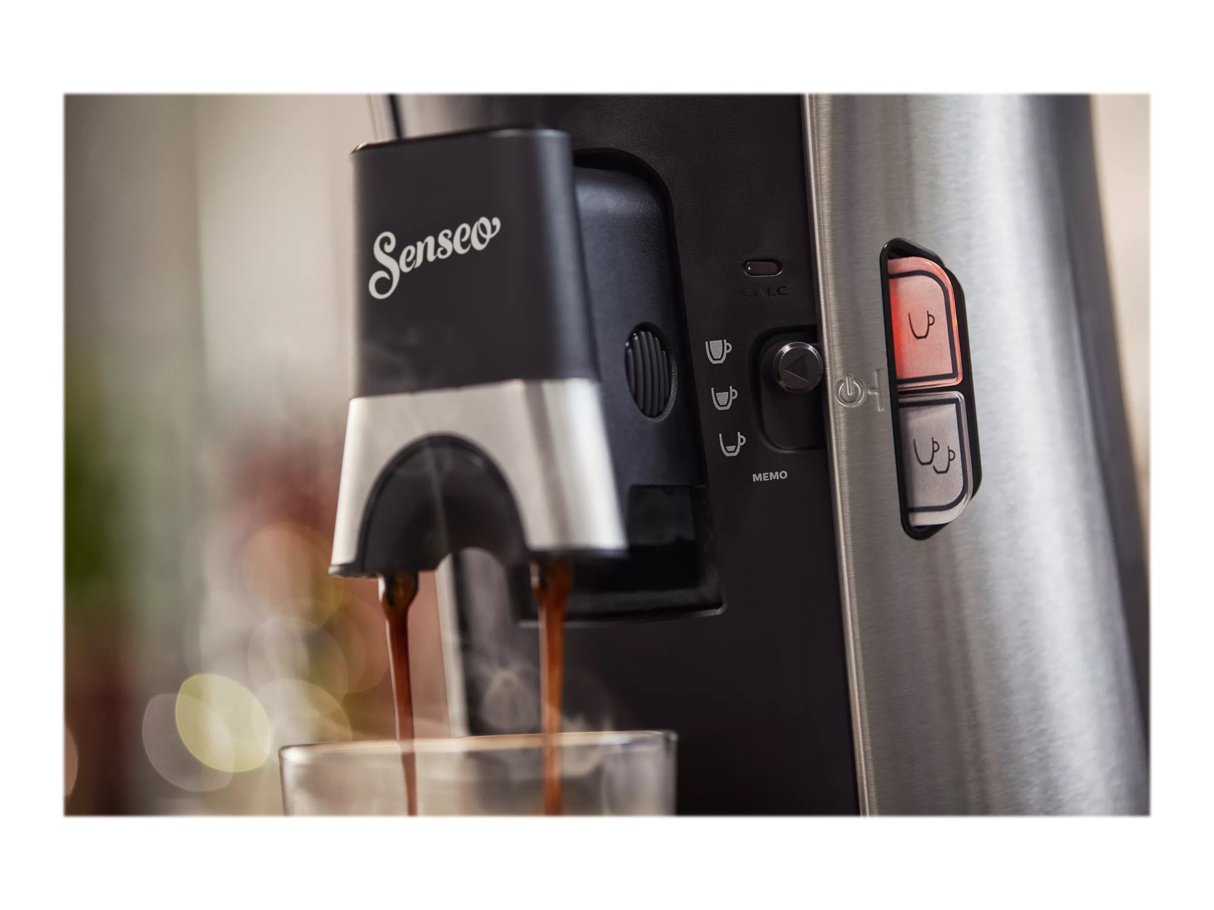 Nahaufnahme einer Kaffeemaschine, die Kaffee in ein Glas ausgibt, mit Bedienelementen und Dampf.