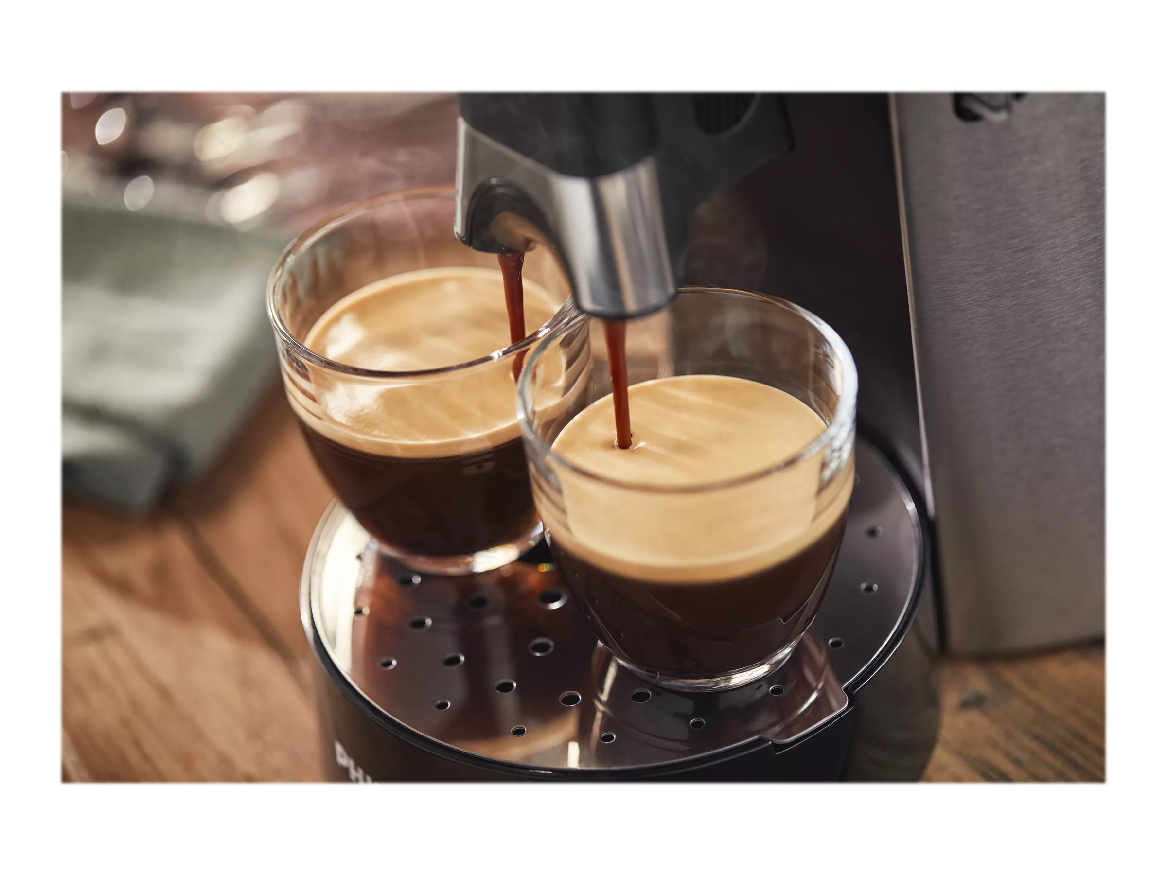 Espressomaschine gießt Kaffee in zwei Glasbecher.