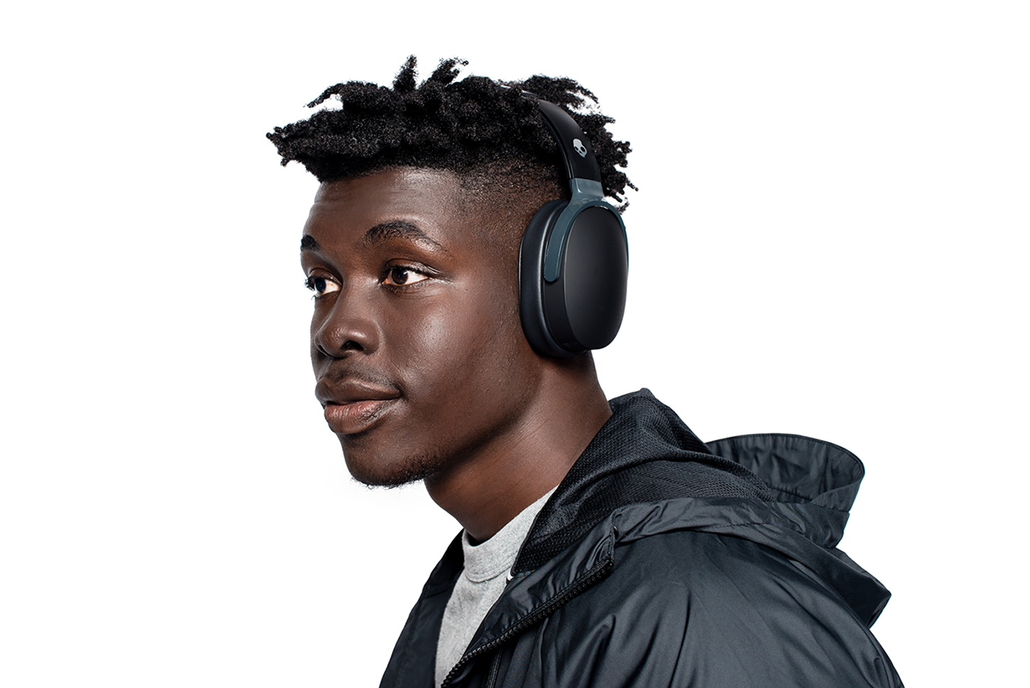 A black man wearing black headphones looks to the left against a white backdrop.