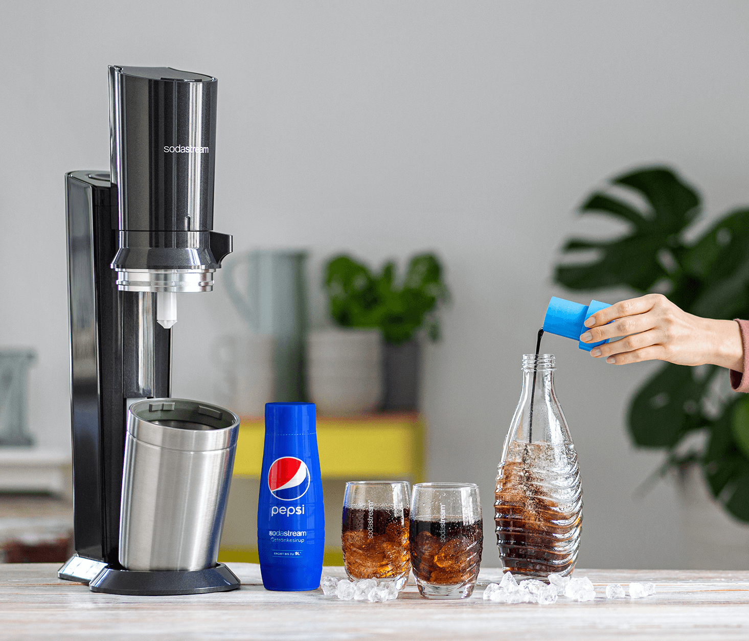 SodaStream-Kohlensäuregerät mit Pepsi und Gläsern mit Limo und Eis.