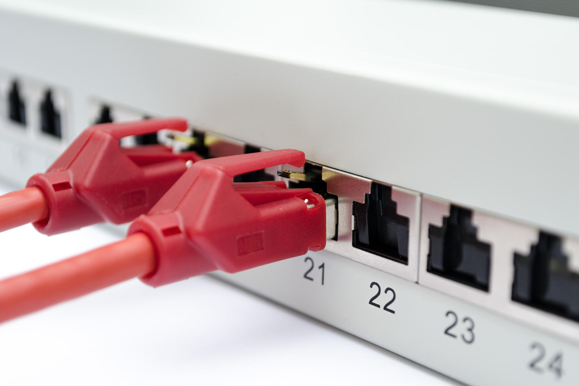 Nahaufnahme eines Netzwerk-Switches mit eingesteckten roten Ethernet-Kabeln. Zahlen sind auf dem Switch.