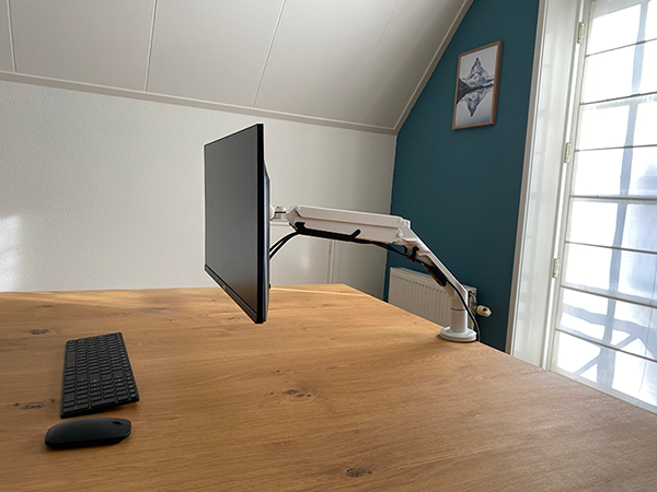 A monitor mounted on a desk, with a keyboard.