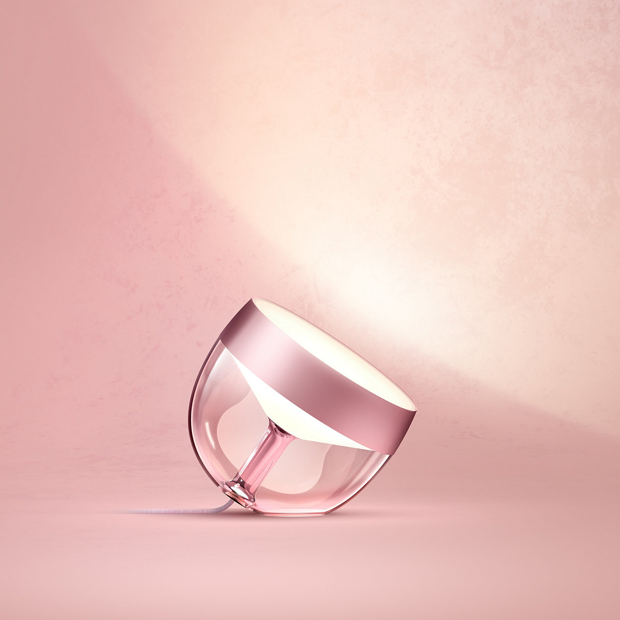 Eine rosa Lampe mit einem roségoldenen Ring und einem rosa Hintergrund.