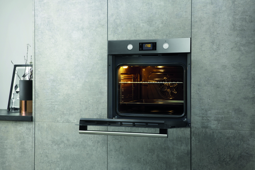 Einbau-Backofen mit geöffneter Tür, eingebaut in eine grau geflieste Wand.