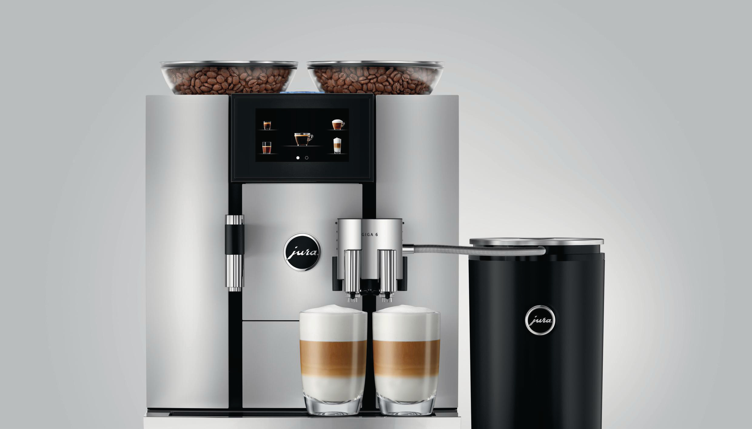Silber-schwarze Kaffeemaschine mit zwei Kaffeetassen und Kaffeebohnen.