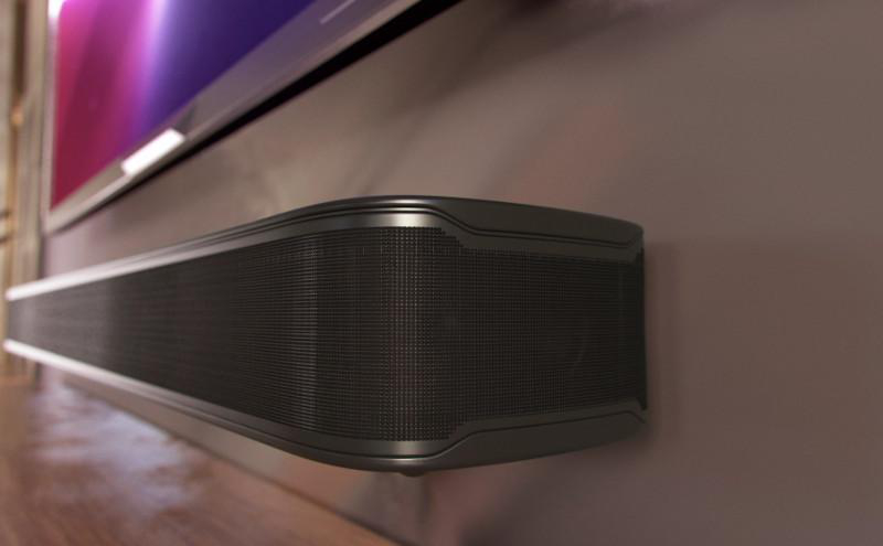 Soundbar unter einem Fernseher an einer Wand montiert. Schwarz, mit Netzfront.