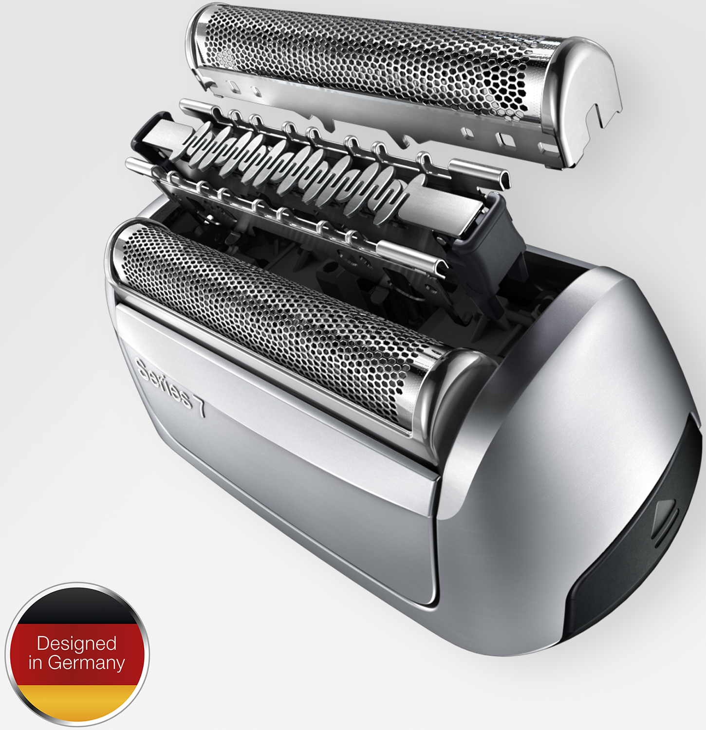 Close-up of a disassembled silver electric shaver. The blades and head are visible. A 'Designed in Germany' sticker is at the bottom.