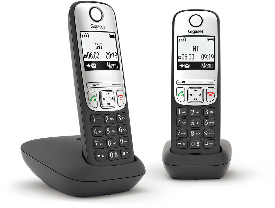 Két vezeték nélküli telefon a töltőjükön. A bal oldali telefon a töltőjében, időt kijelezve.