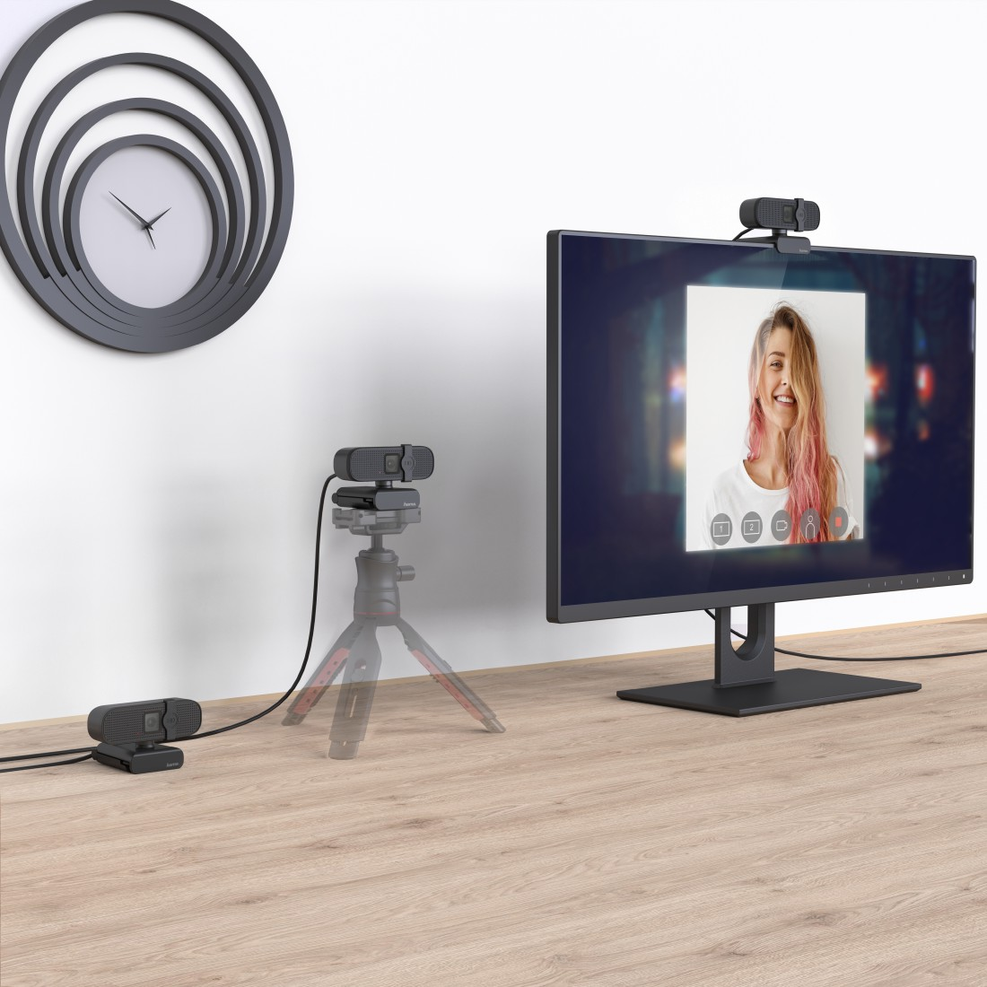 Ein Schreibtisch mit zwei Webcams, ein Monitor zeigt eine lachende Frau.