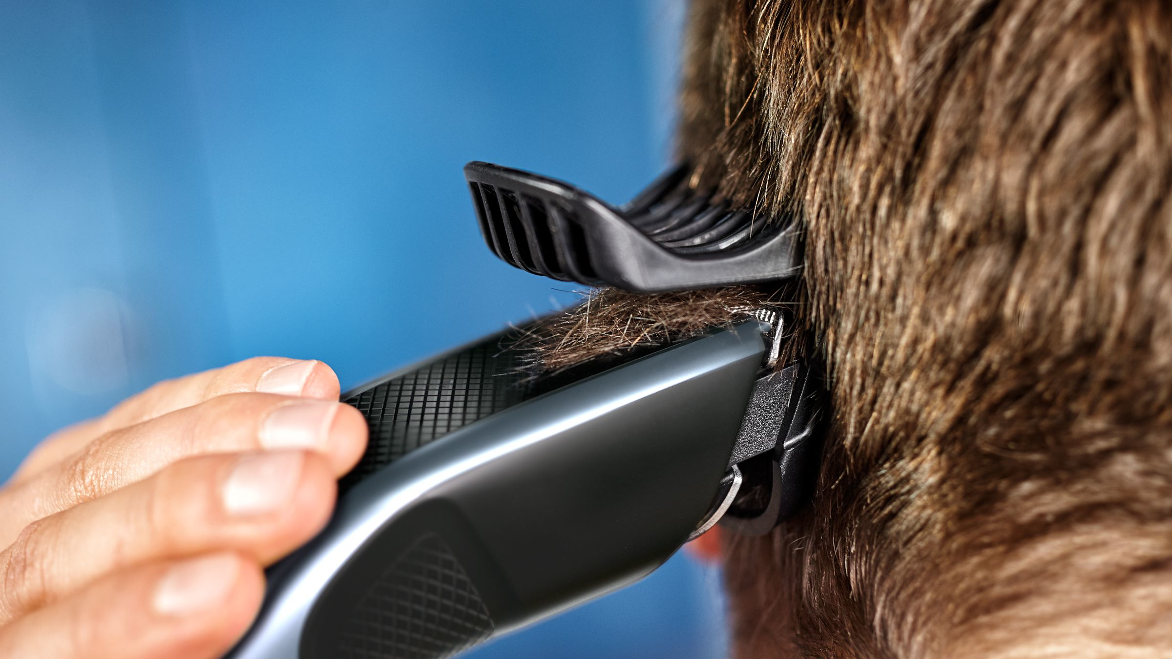 Primer plano de una persona cortándose el pelo con un cortapelos.