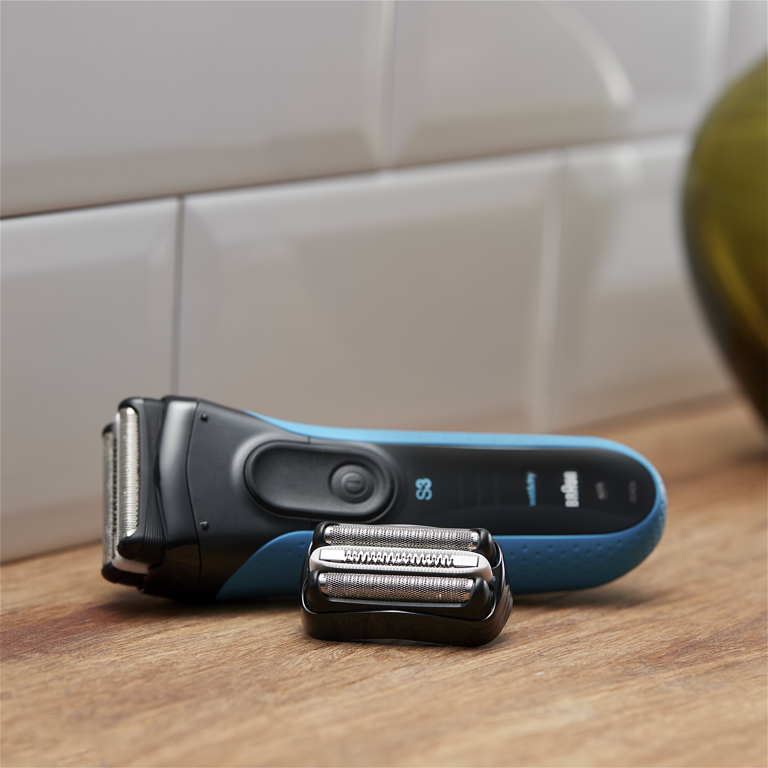 A Braun shaver with its replacement head on a wood surface.