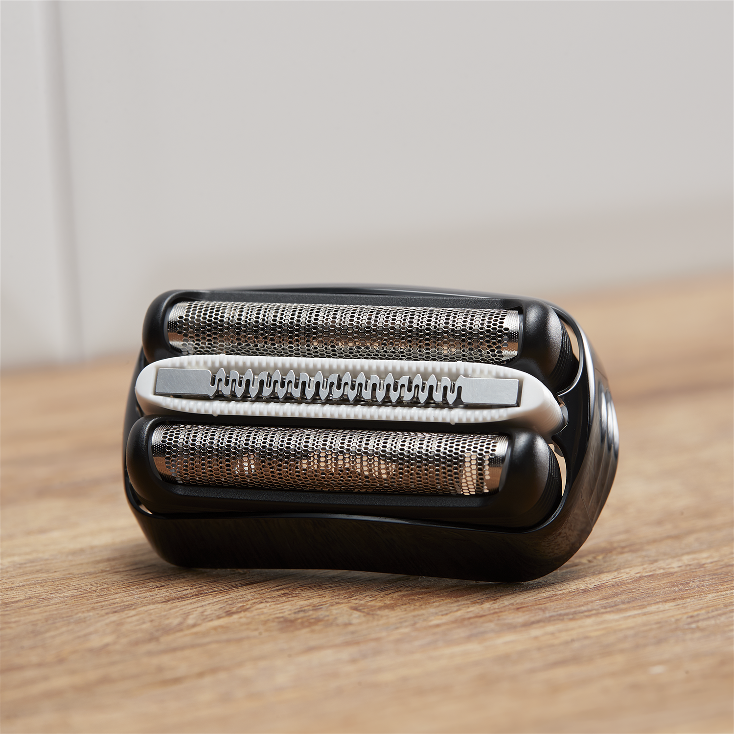 Close-up of a shaver head with three blades. The blades are silver and the body is black.