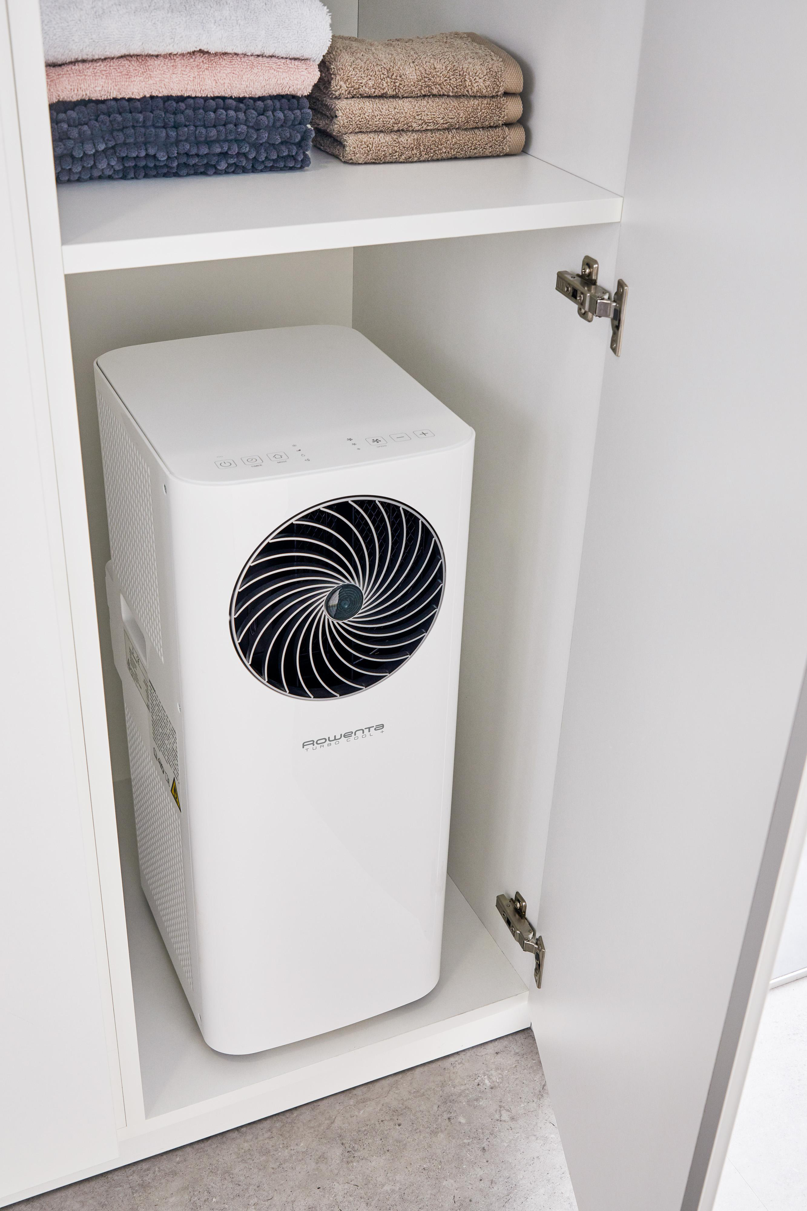 Ein weißer Rowenta Luftreiniger in einem weißen Schrank mit Handtüchern.