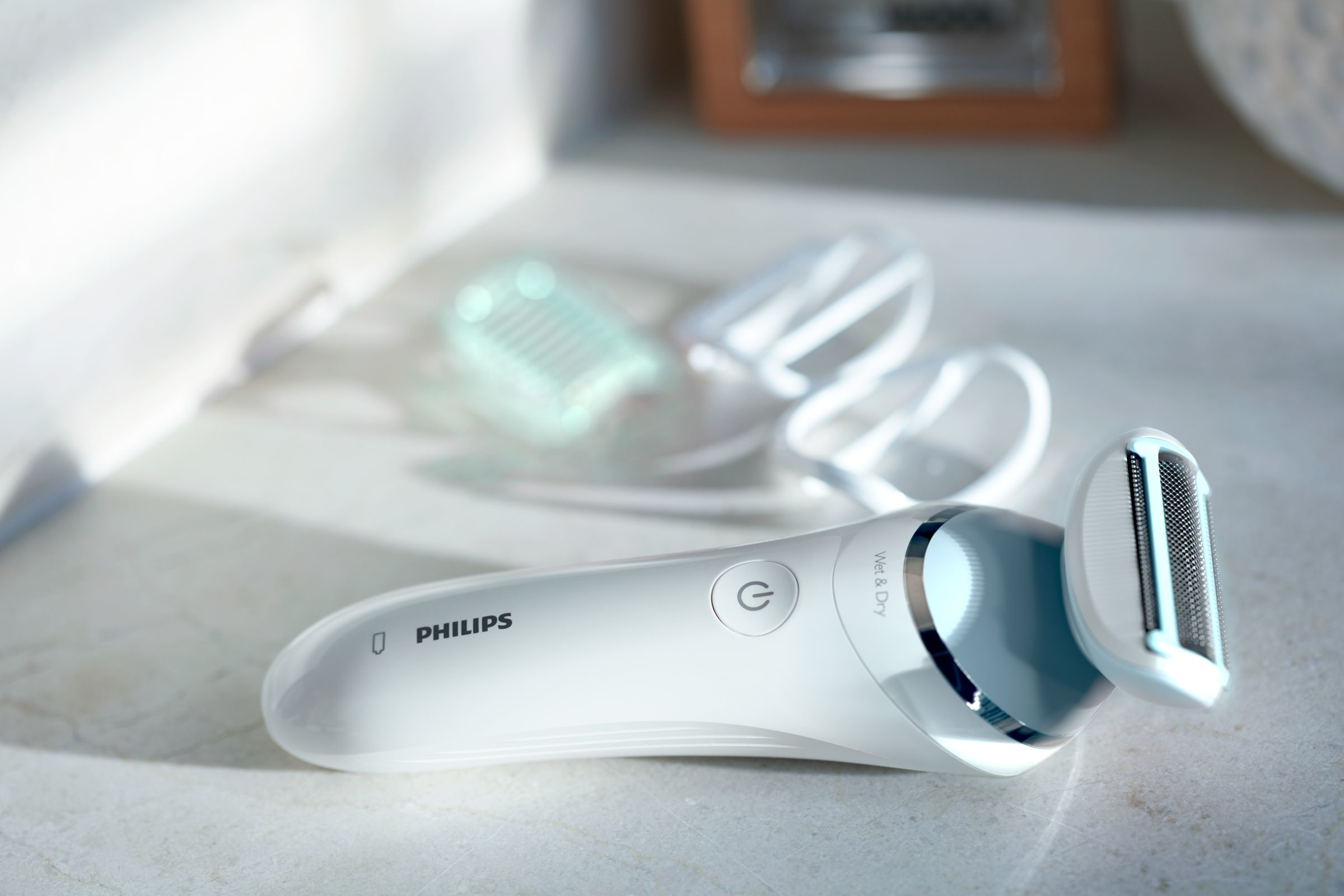 Una afeitadora eléctrica Philips blanca y azul sobre una superficie clara.