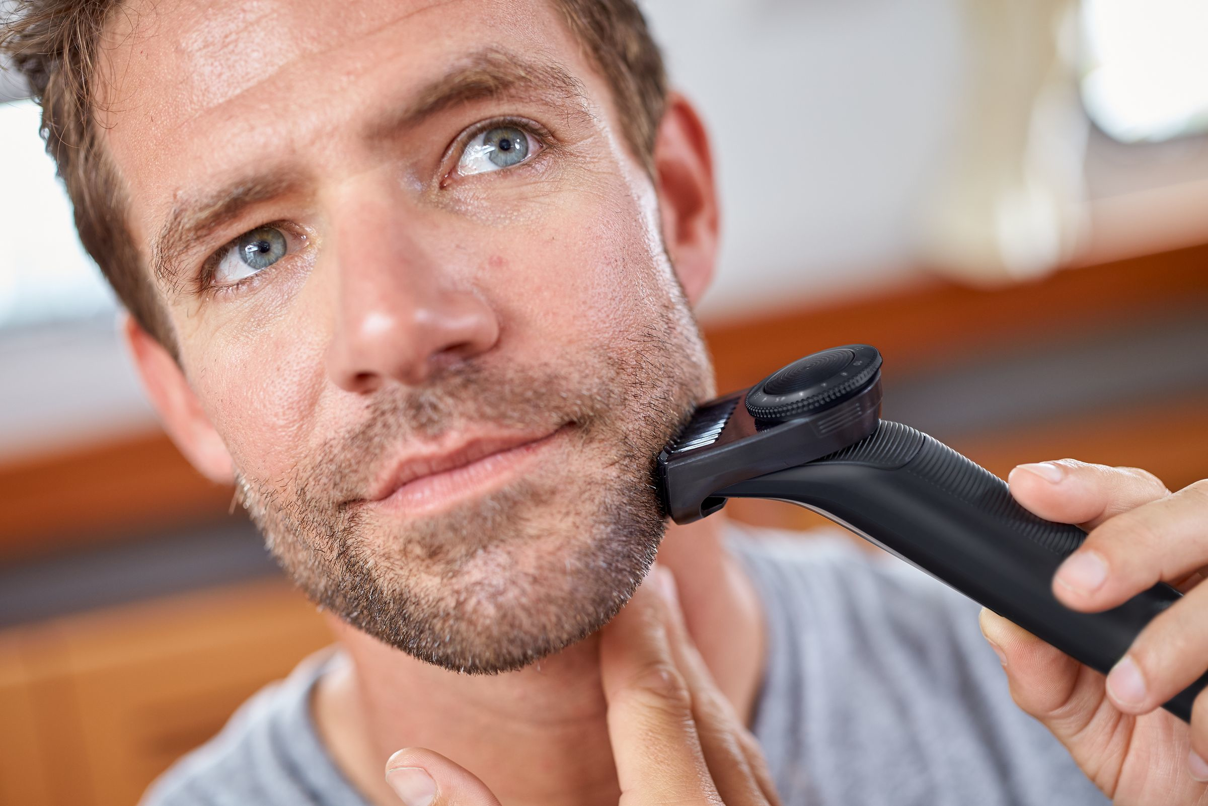 Hombre afeitándose la barba con una recortadora eléctrica, toma de cerca.