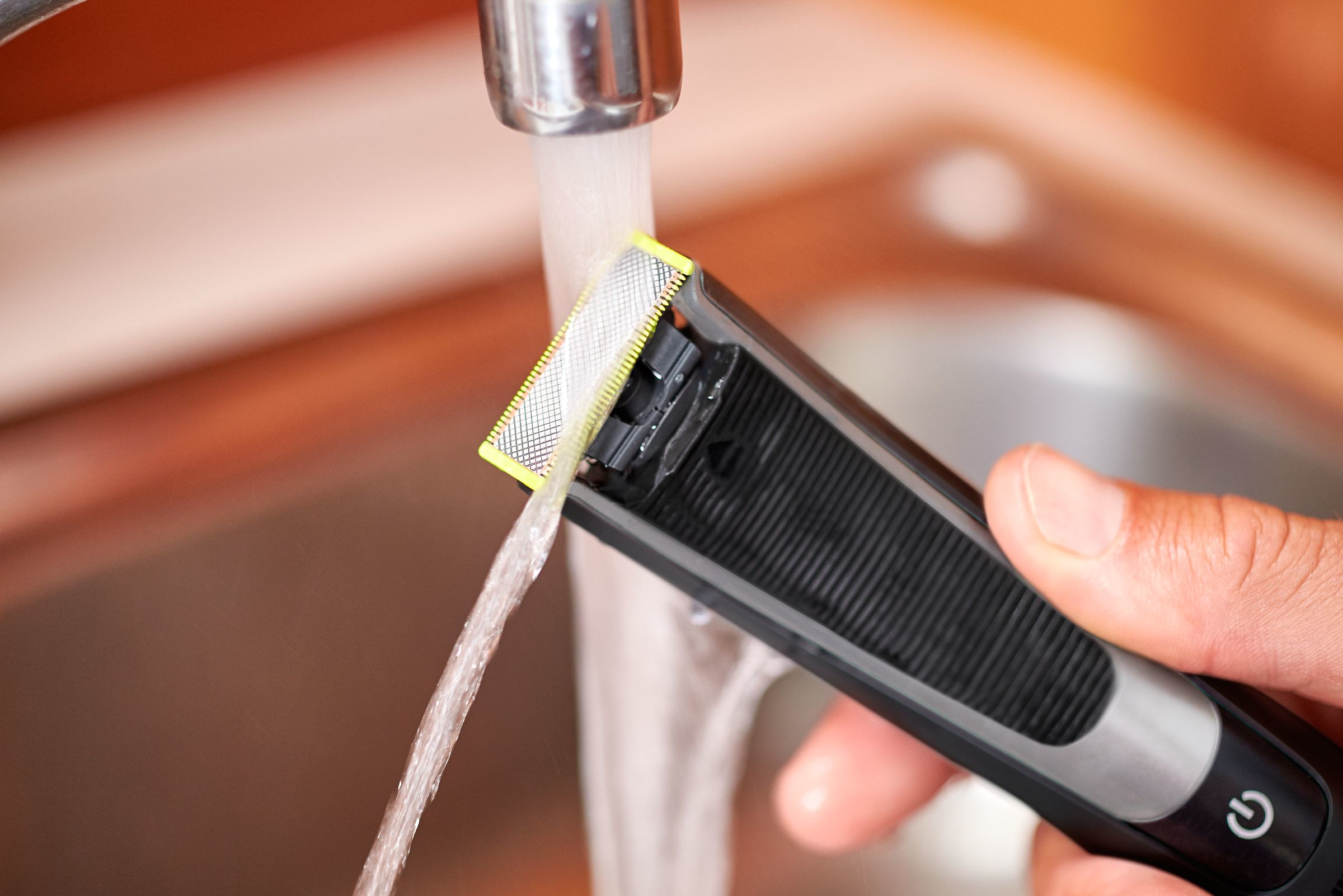Una recortadora se lava con agua en el fregadero. La cuchilla es visible.