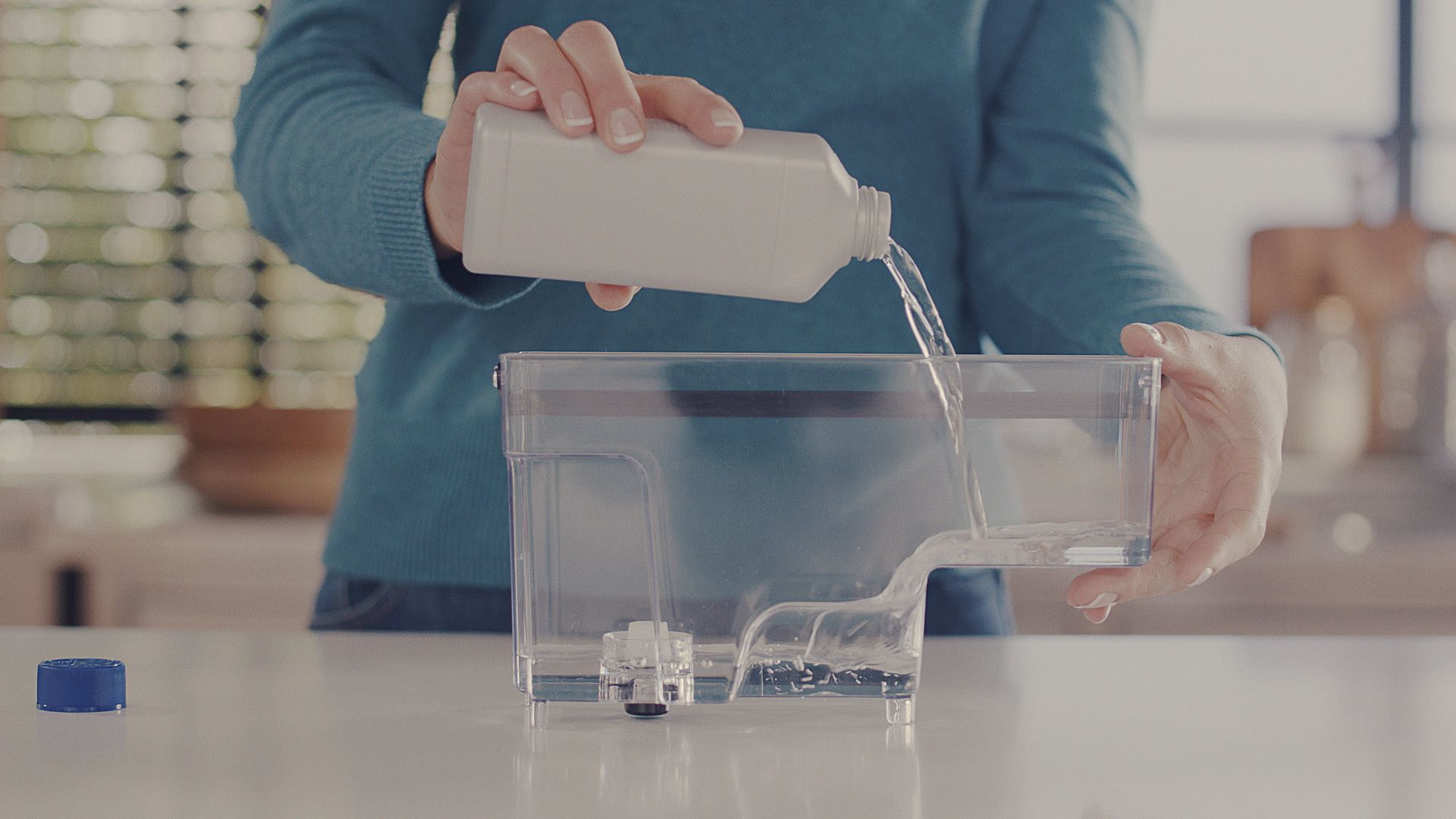 Una persona vierte líquido de una botella blanca a un recipiente transparente.