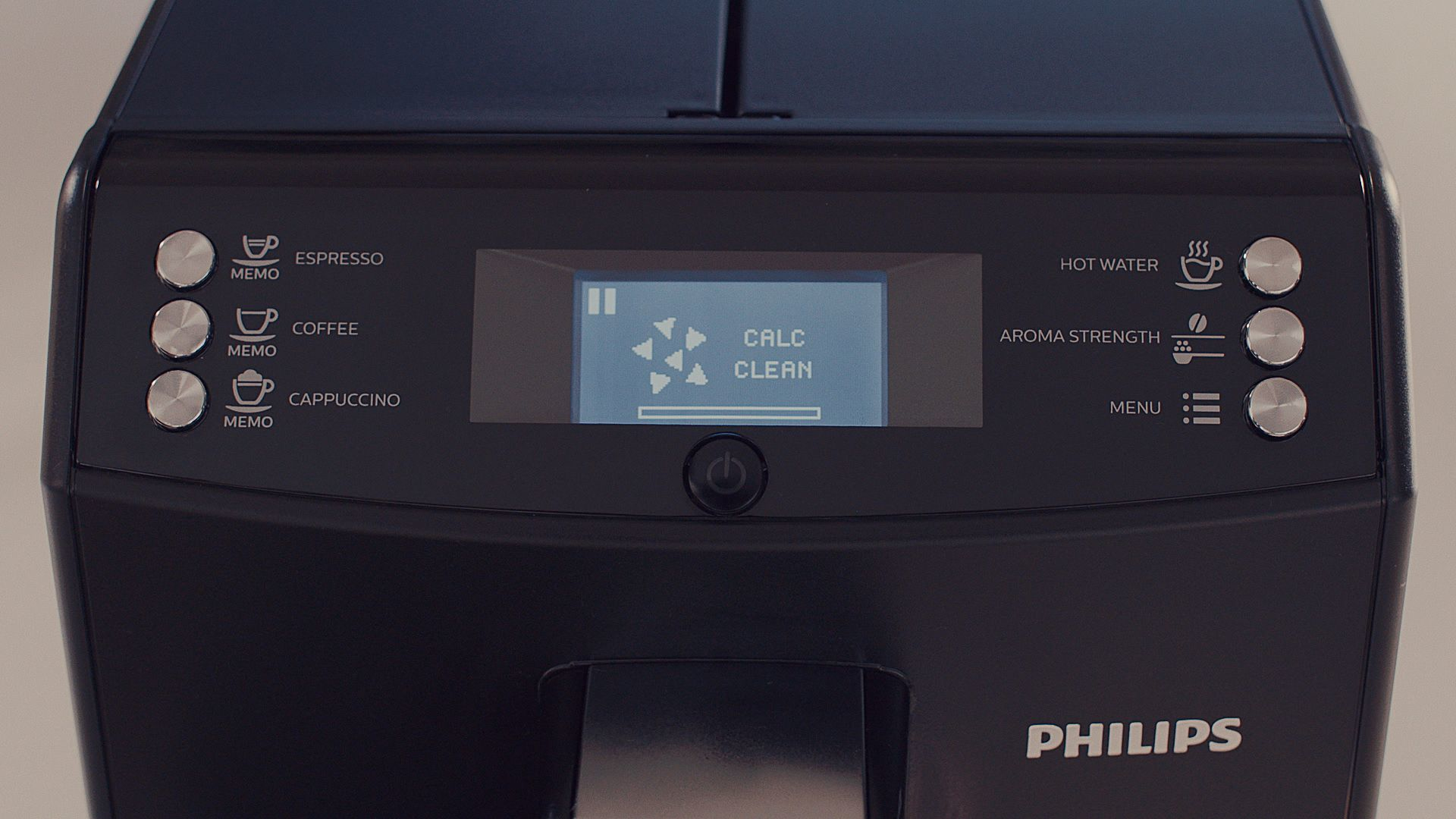 Pantalla de cafetera Philips que muestra Calc/Clean. Máquina negra, fondo blanco.