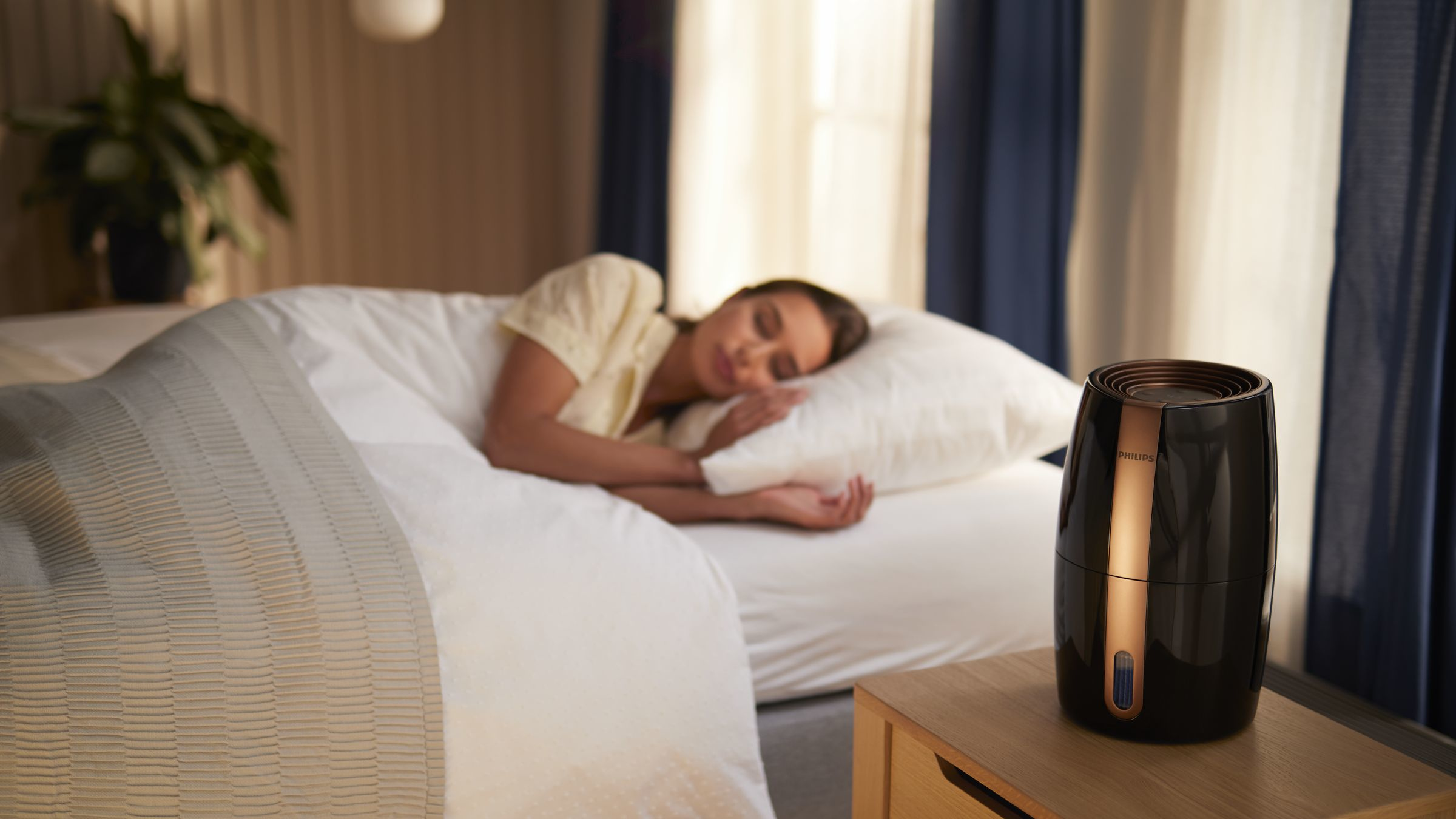 Een vrouw die in bed slaapt met een luchtbevochtiger op een nachtkastje.