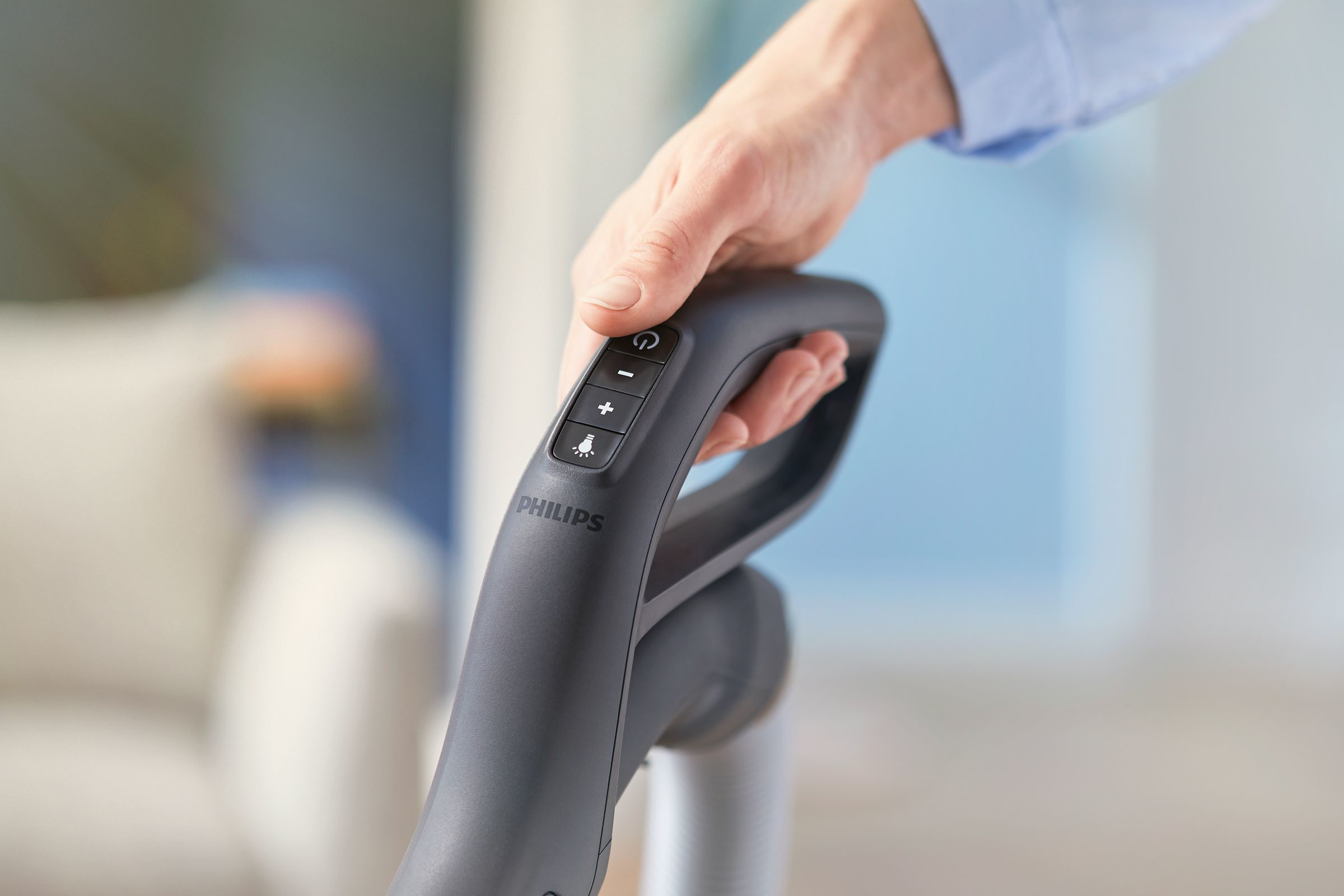 El, elektrikli süpürgenin sapındaki bir düğmeye basıyor.