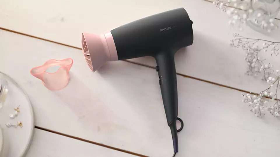 Sèche-cheveux Philips noir et rose et un diffuseur rose.
