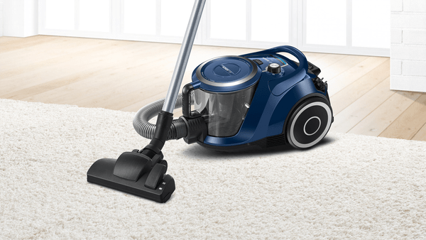 Ein blauer Staubsauger auf einem weißen Teppich mit Zubehör.