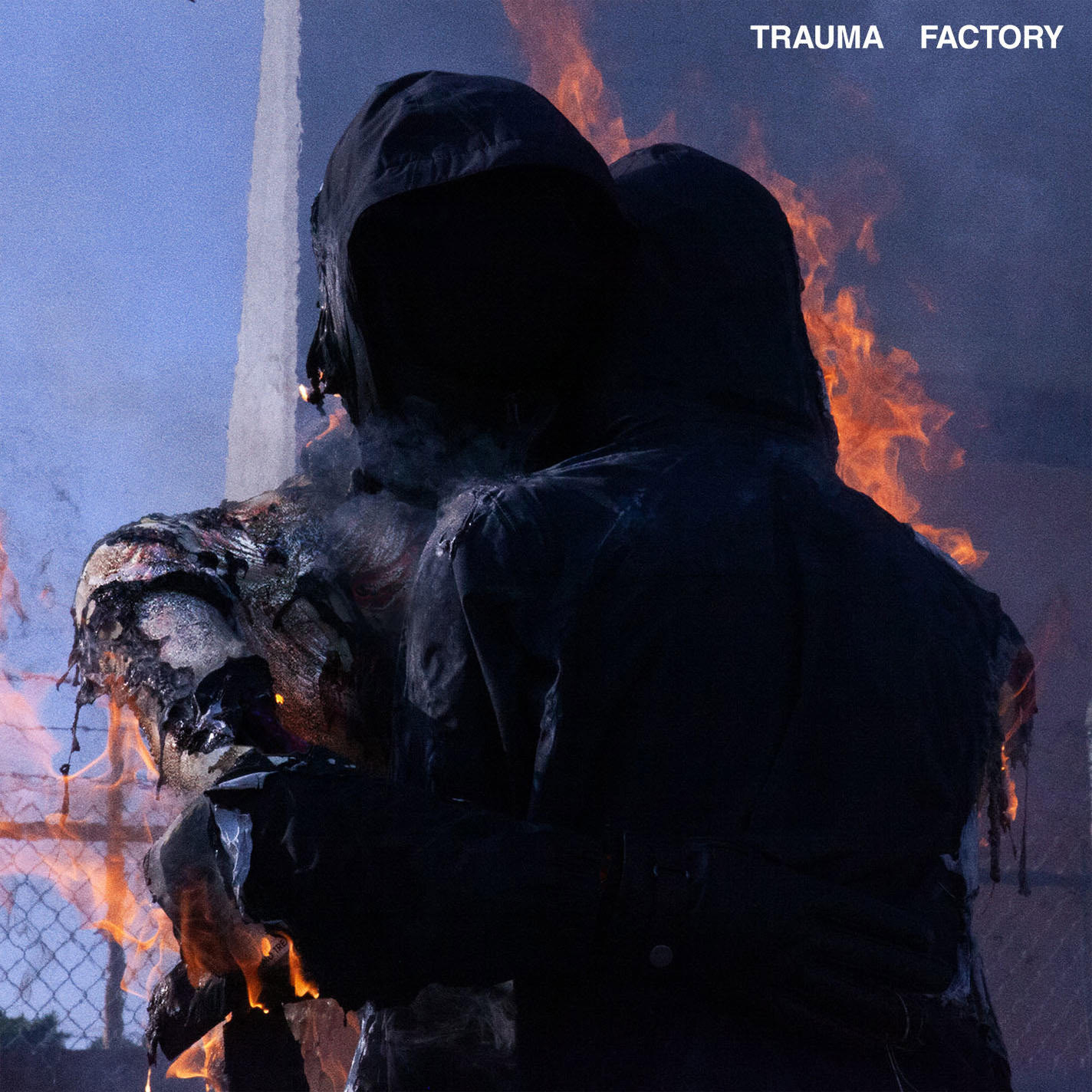Zwei vermummte Gestalten umarmen sich, eine davon brennt. Flammen umgeben sie. Der Himmel ist ein Farbverlauf aus Blau und Orange. Oben steht "TRAUMA FACTORY".