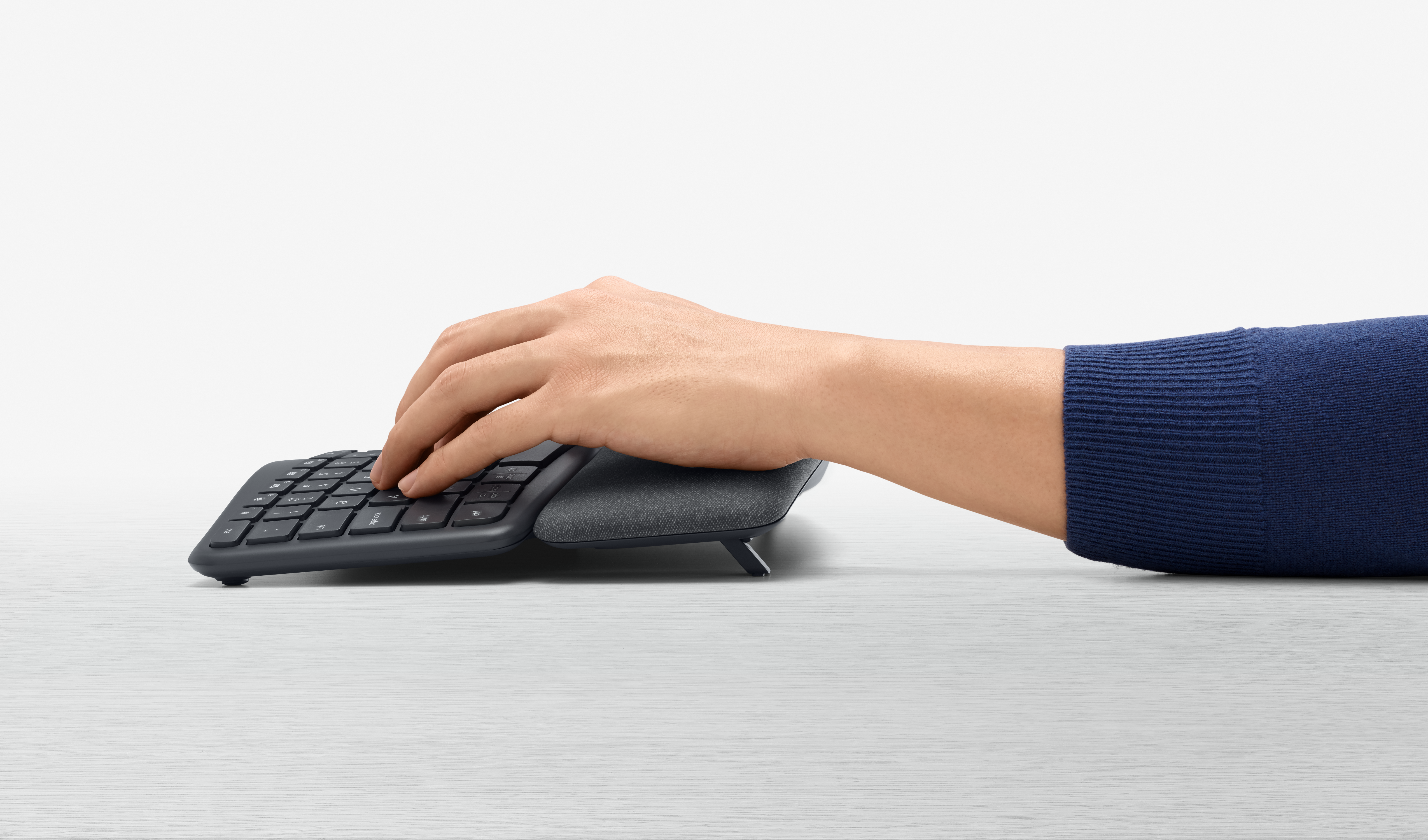La mano di una persona su una tastiera ergonomica Logitech.