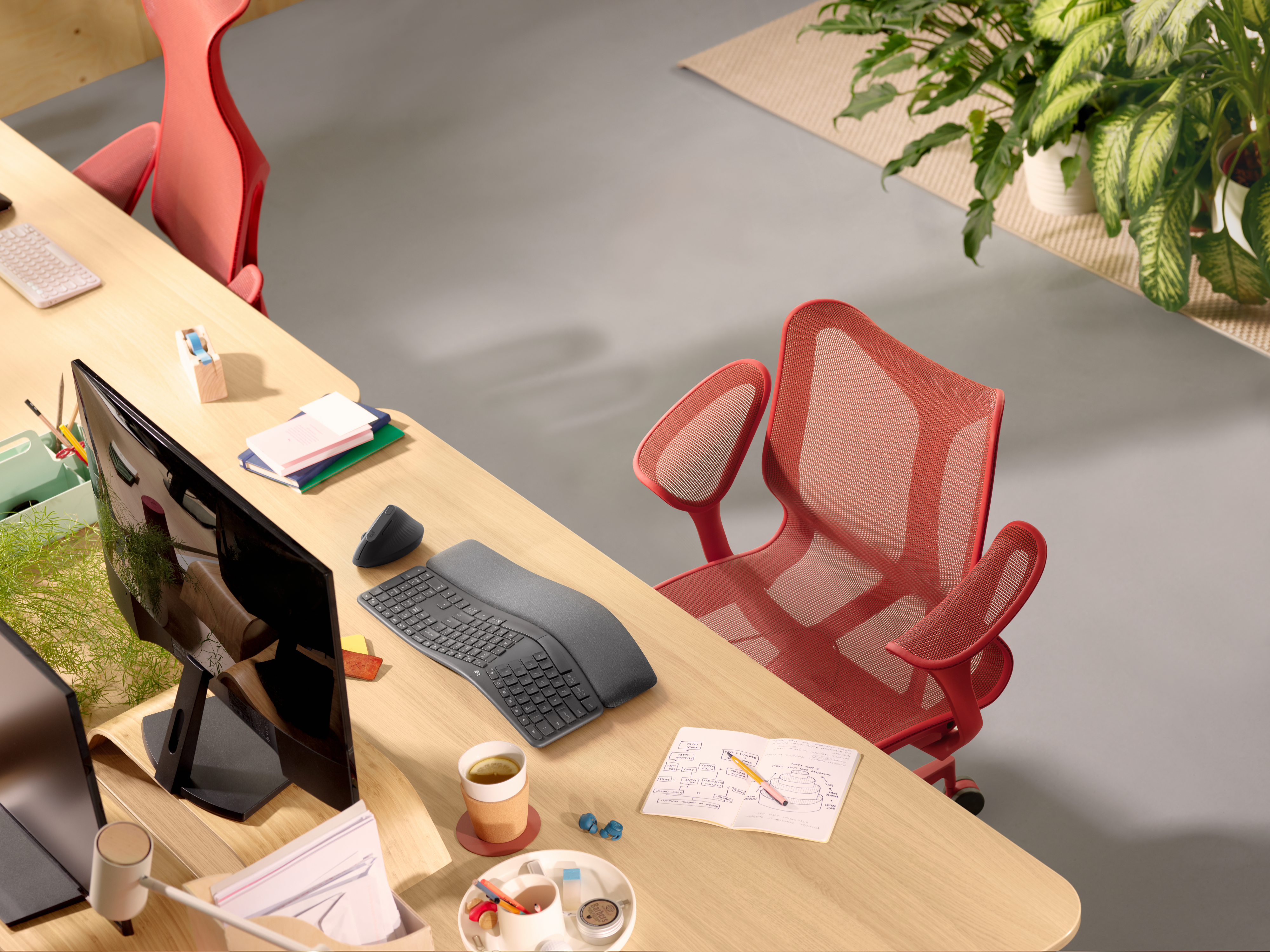 Spazio di lavoro in ufficio: scrivania con monitor, tastiera, mouse e una sedia da ufficio rossa.