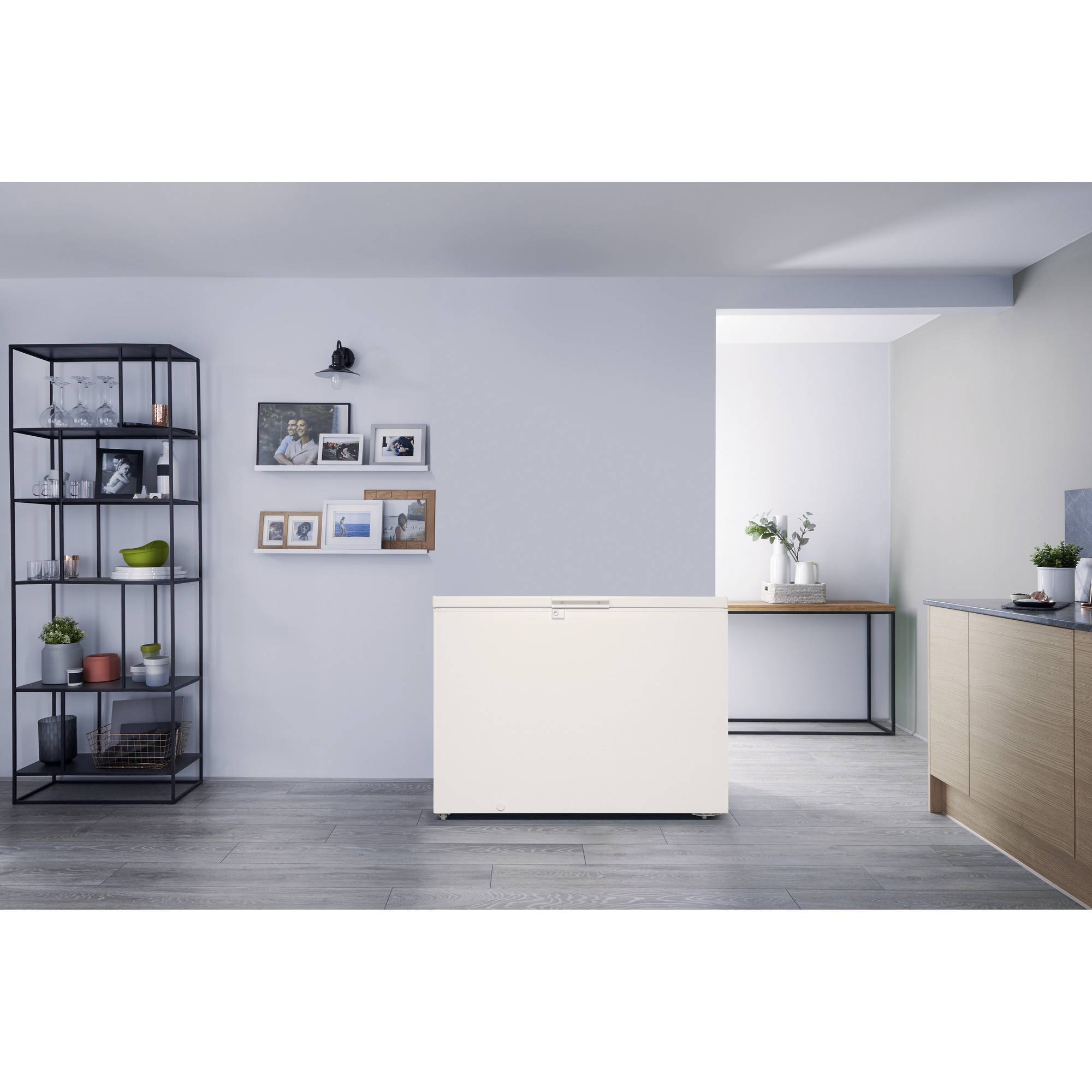 Ein weißer Gefrierschrank in einer modernen Küche mit Regalen, Bildern und einem Holztisch.