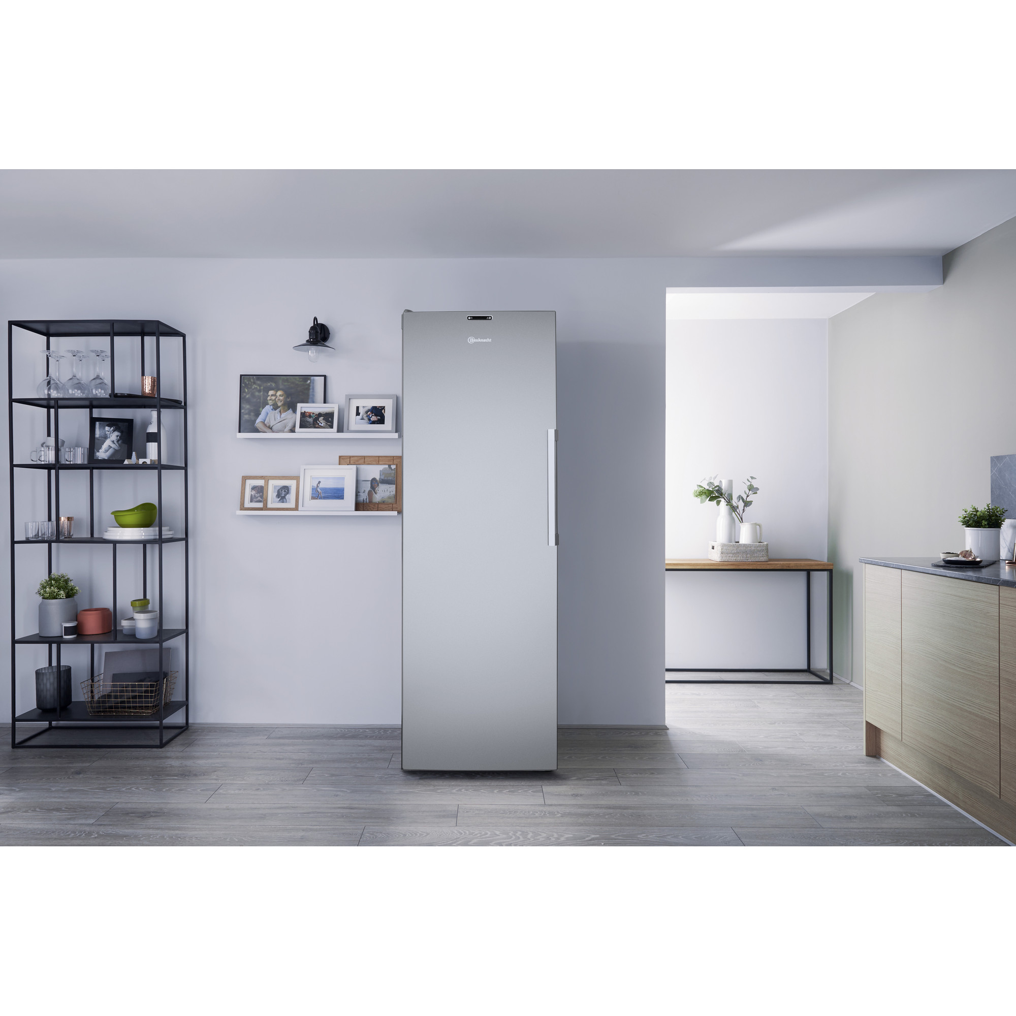 Ein silberner Kühlschrank neben einem schwarzen Regal und einer Holztheke.