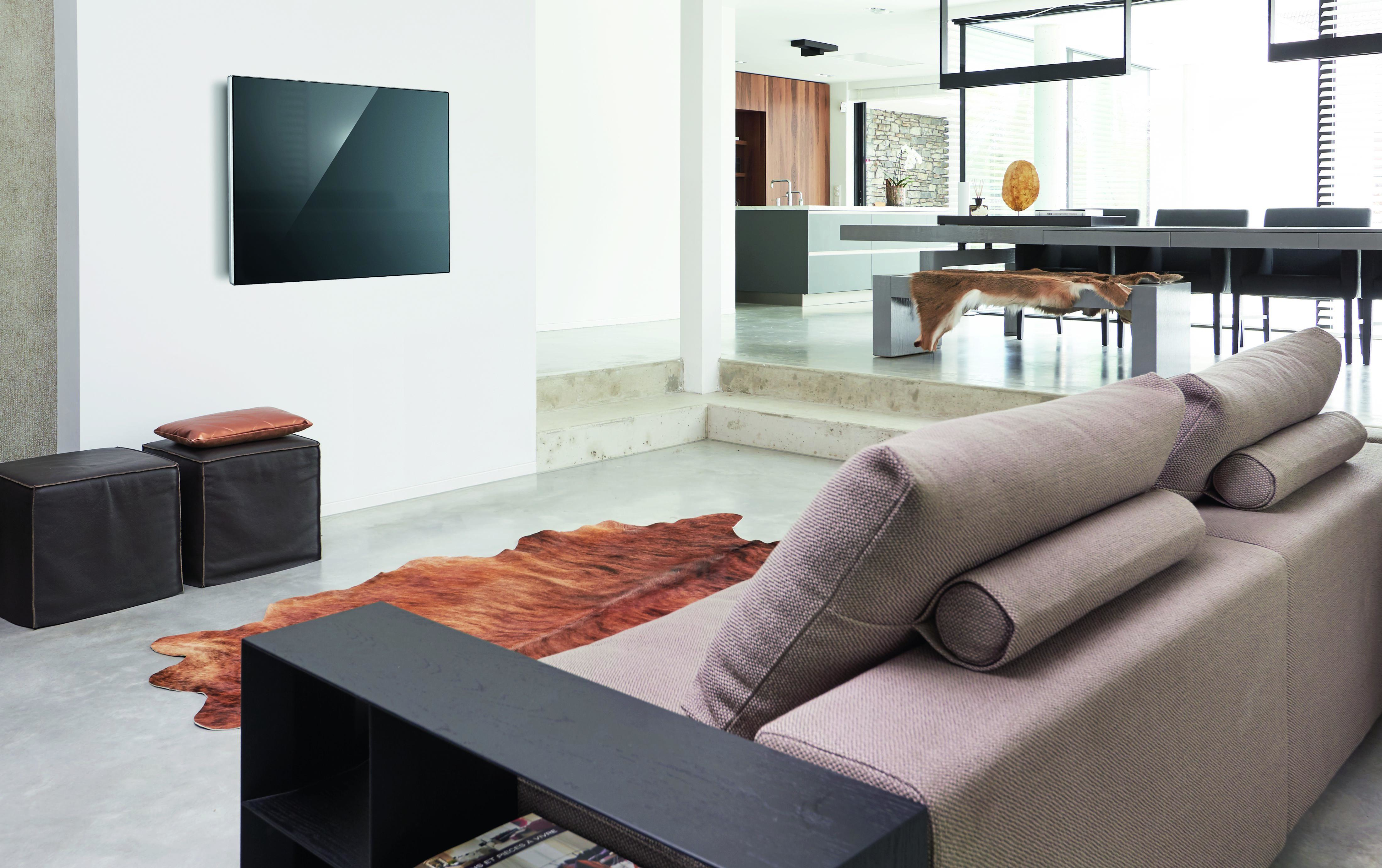 Een woonkamer met een aan de muur gemonteerde tv.