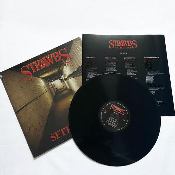 Eine Vinyl-Schallplatte und Hülle für Strawbs' Album 'Settlement' auf weißem Grund.